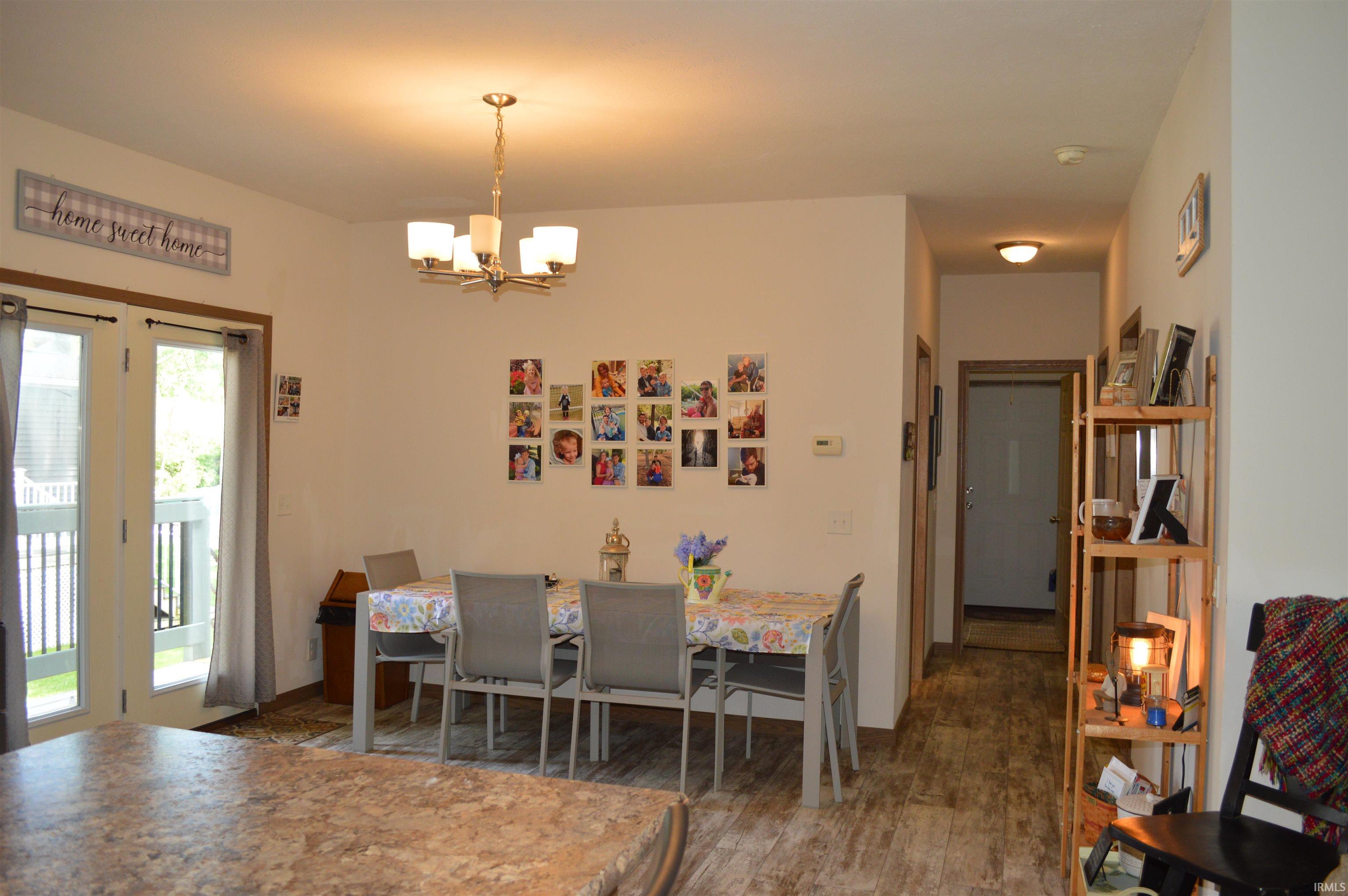 Dining area featuring a contemporary chandelier, French doors opening to an exterior deck, and wood-finish flooring