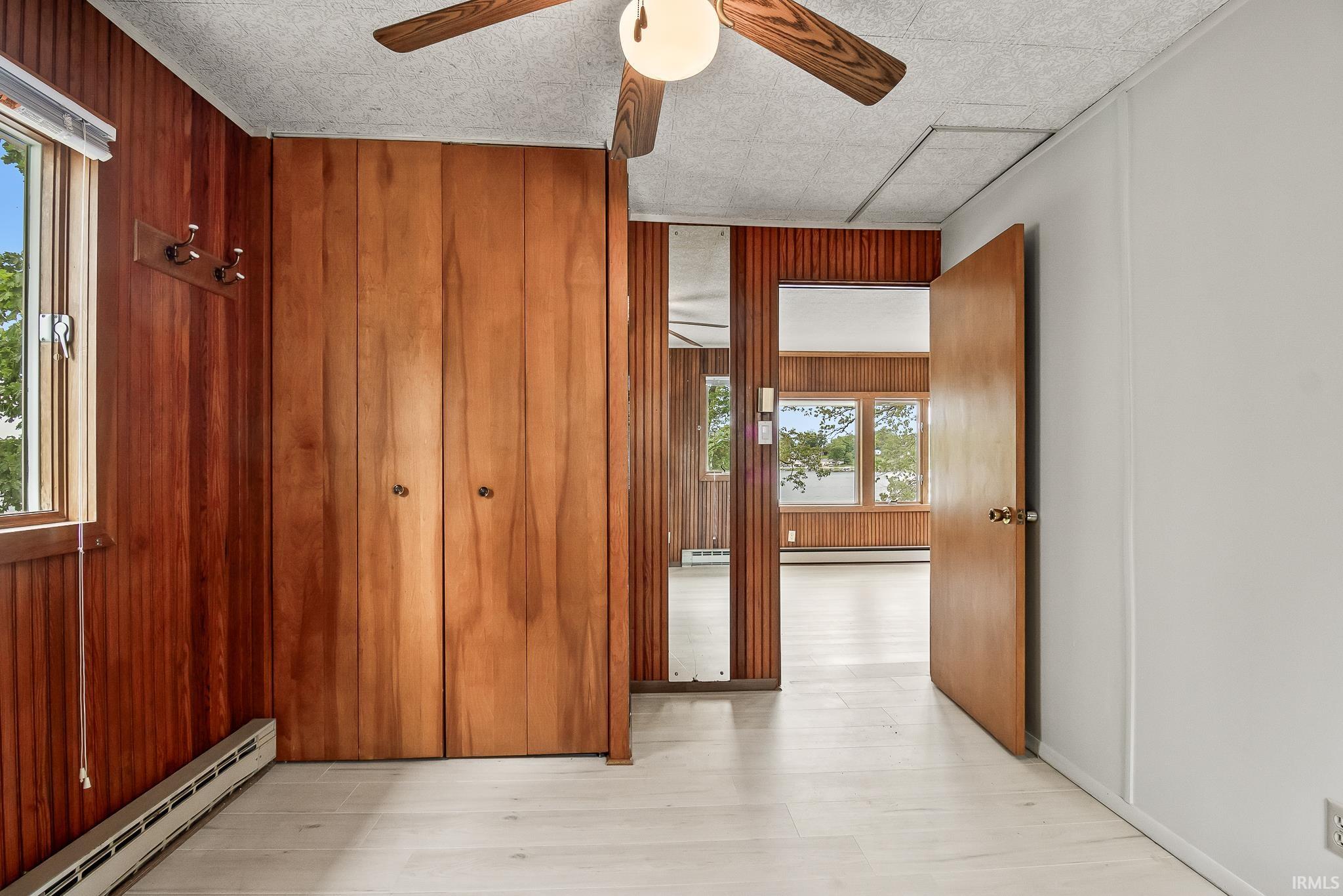 Interior room featuring light-toned flooring, wood paneling, and a built-in closet with double doors