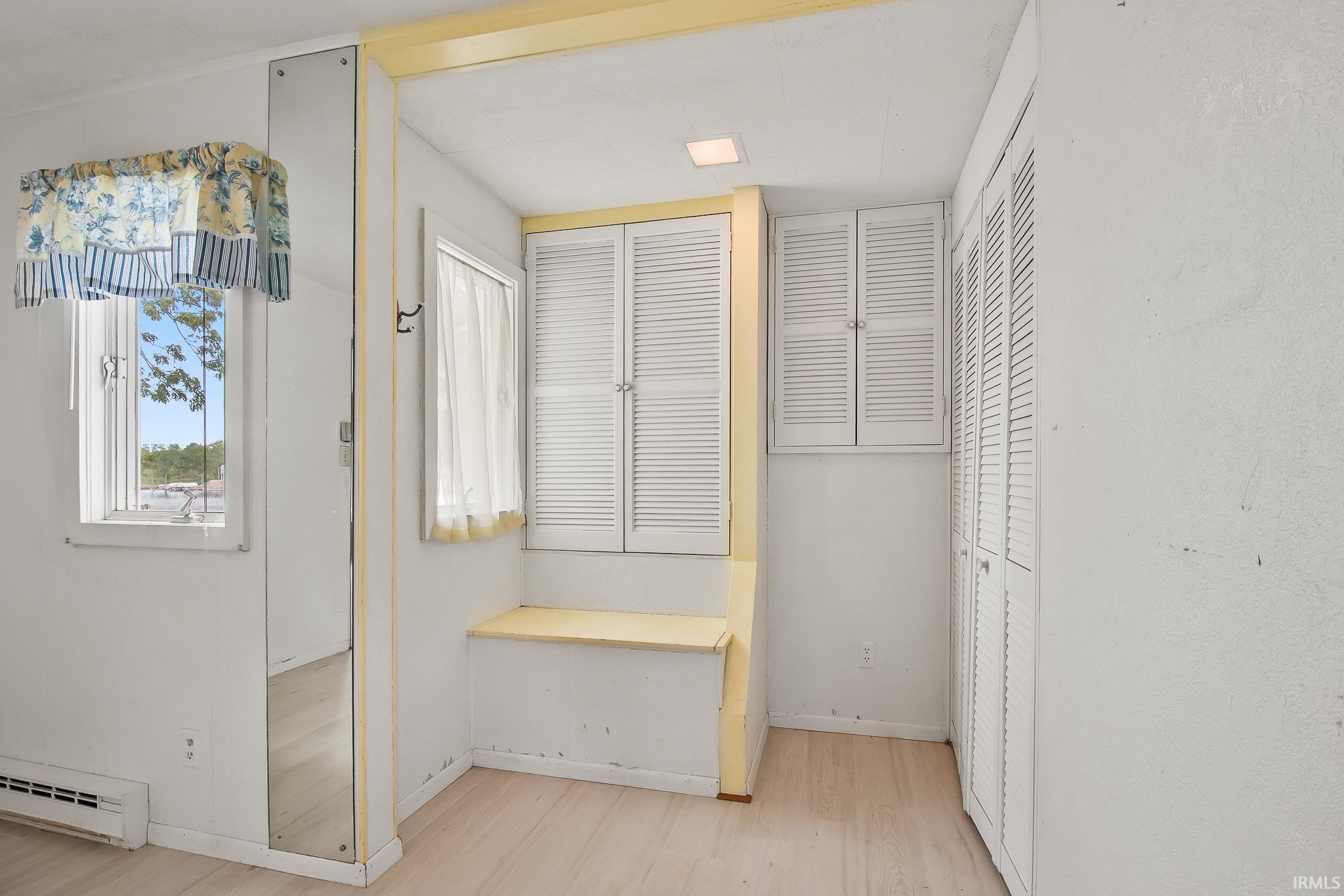 Room featuring light wood-finish flooring, white walls, and a built-in window seat with storage
