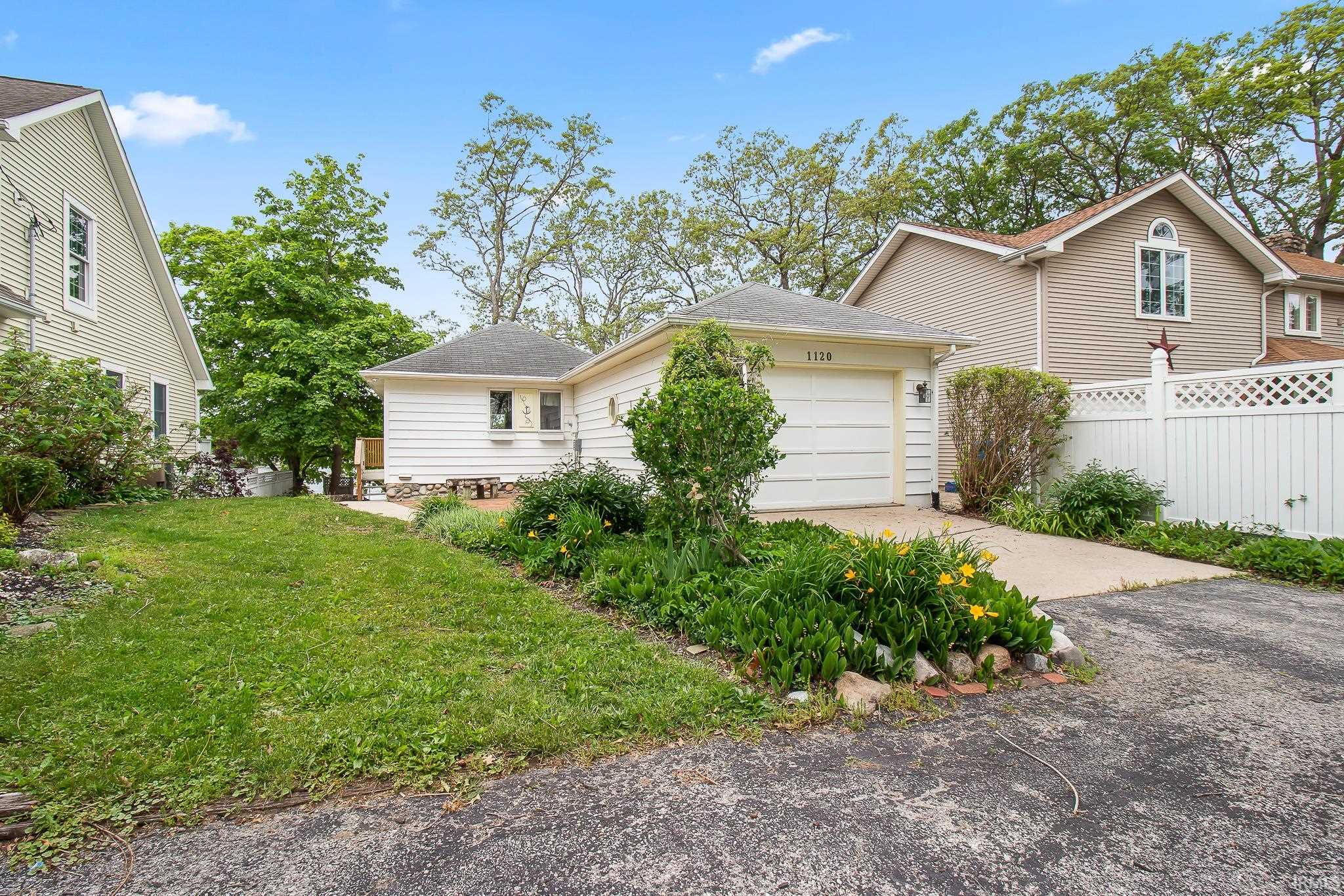 Front exterior featuring a single-car garage, concrete driveway, and mature landscaping