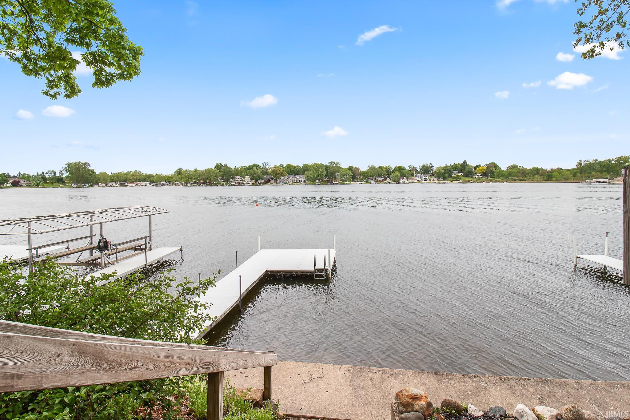 Expansive waterfront featuring multiple docks, a covered boat lift, and concrete steps leading to the water's edge