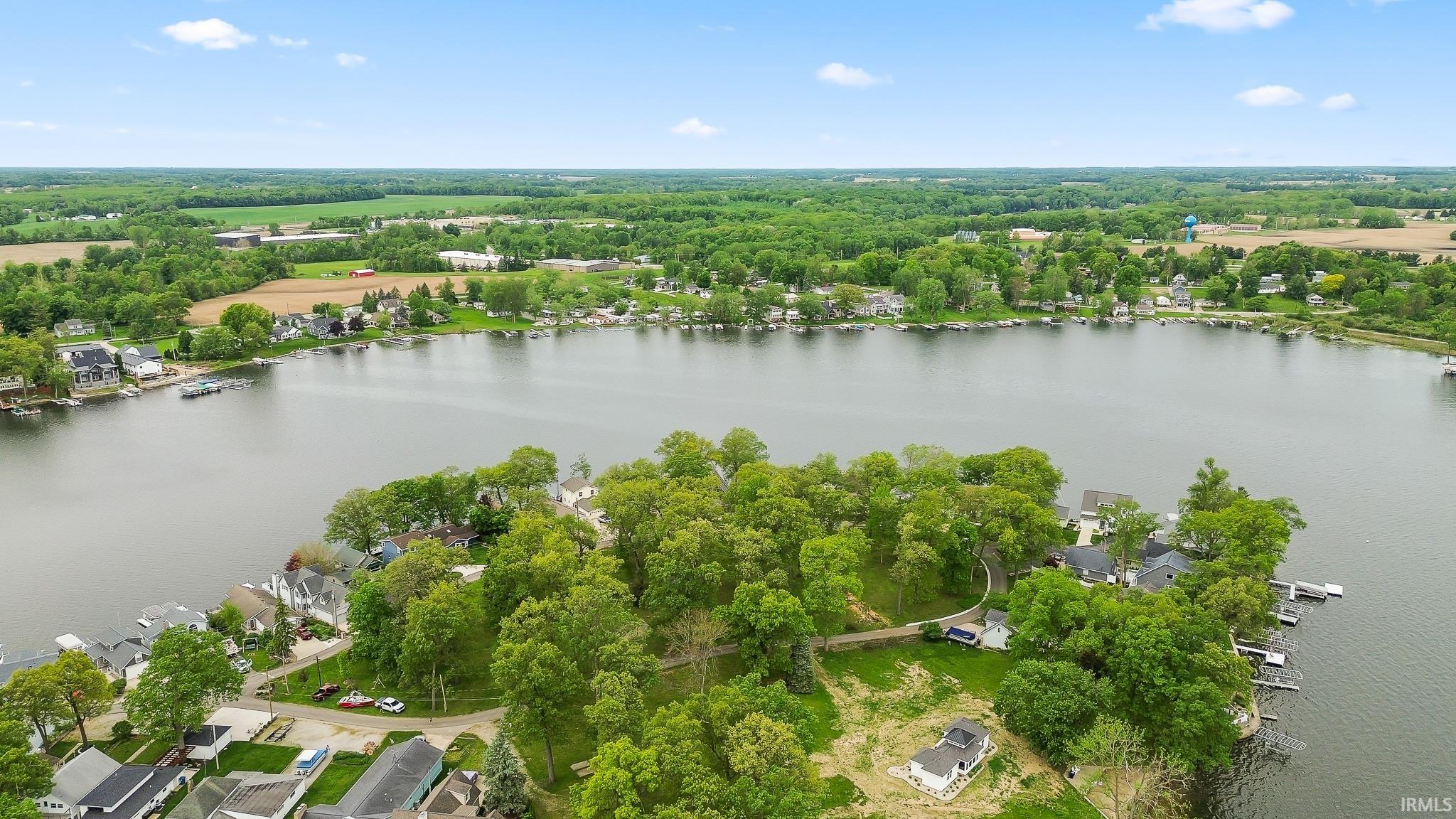 Aerial perspective showcasing a large body of water, bordered by residential properties and mature trees