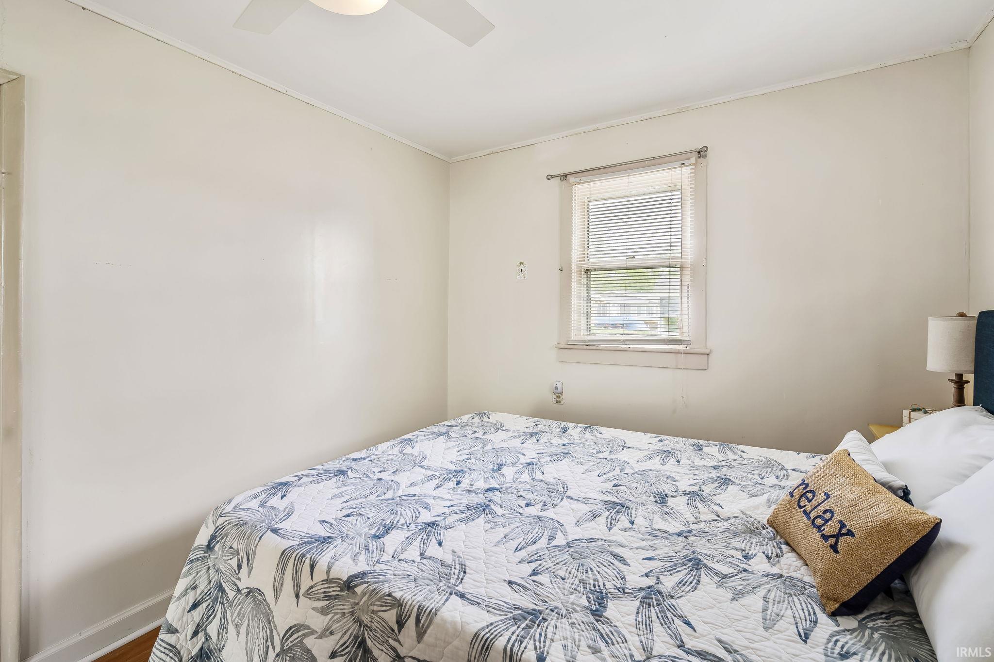Bedroom featuring a ceiling fan, a single window with blinds, and light-toned walls