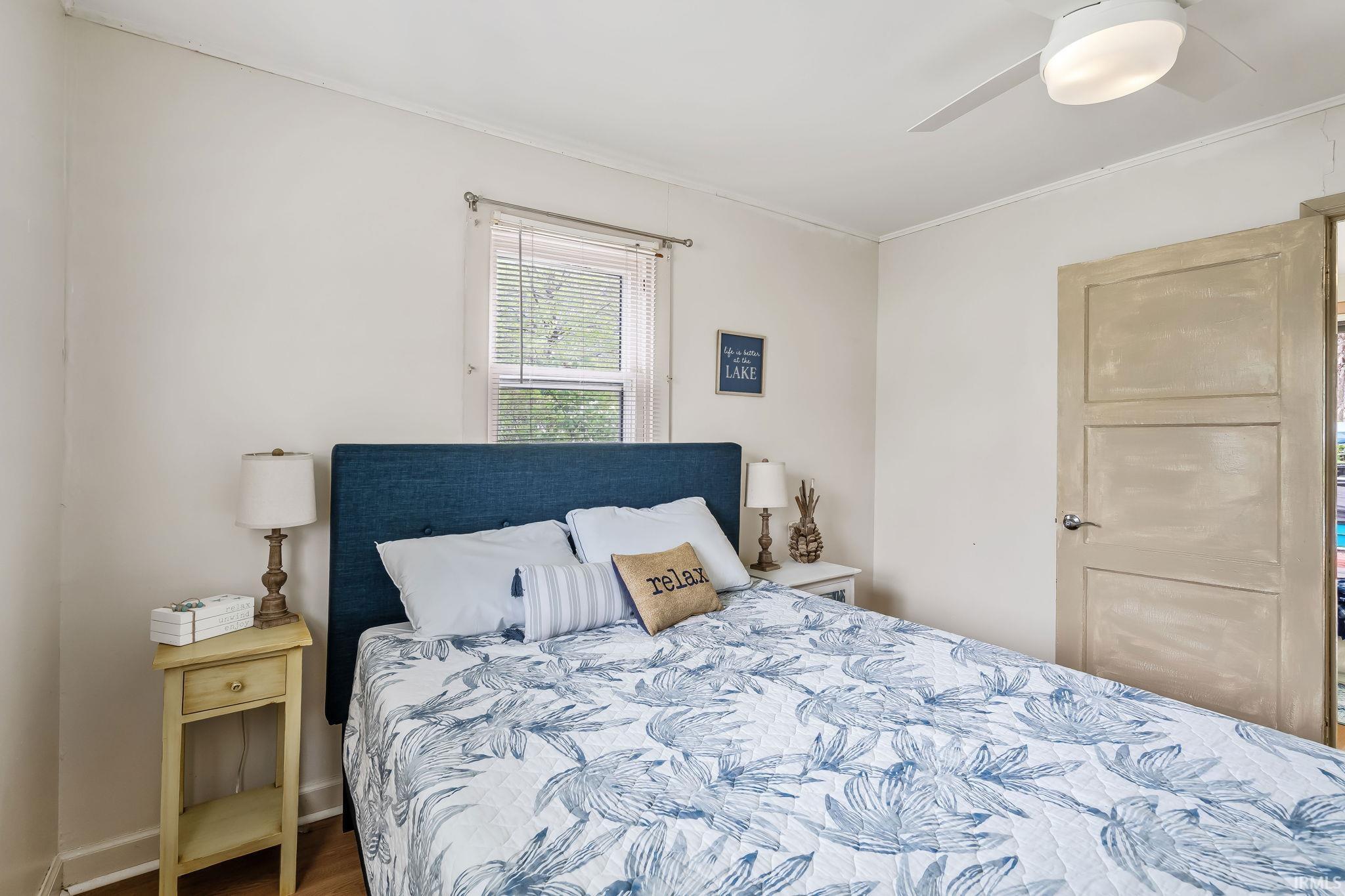 Bedroom featuring a panel door, ceiling fan, and wood-finish flooring