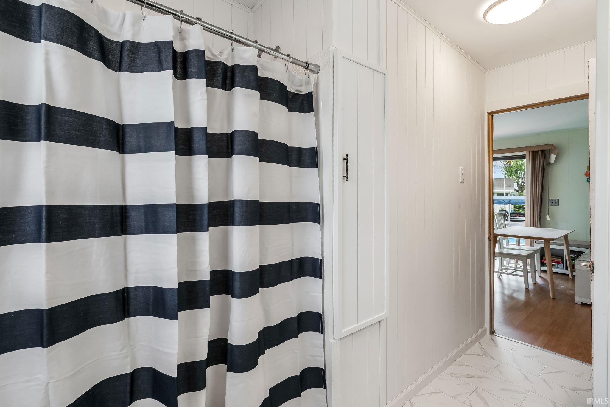 White shiplap walls featuring an integrated storage cabinet and overhead flush-mount lighting