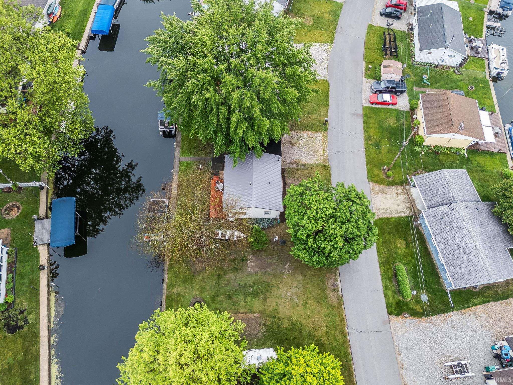 Waterfront property featuring a canal, mature trees, and a paved street