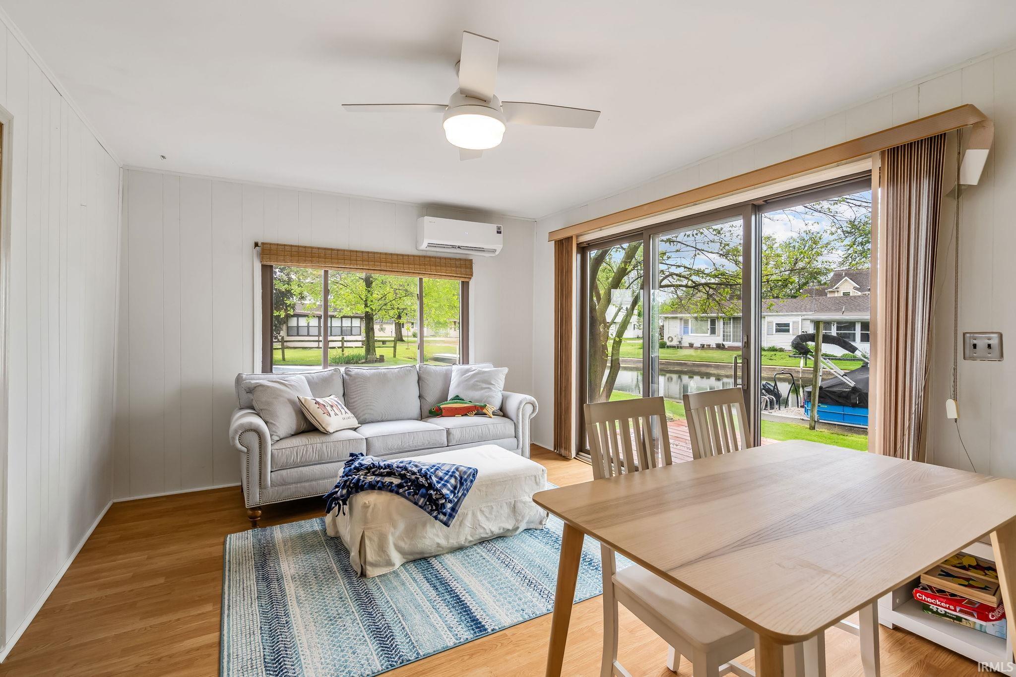 Living area featuring wood-finish flooring, white paneling, and a contemporary ceiling fan