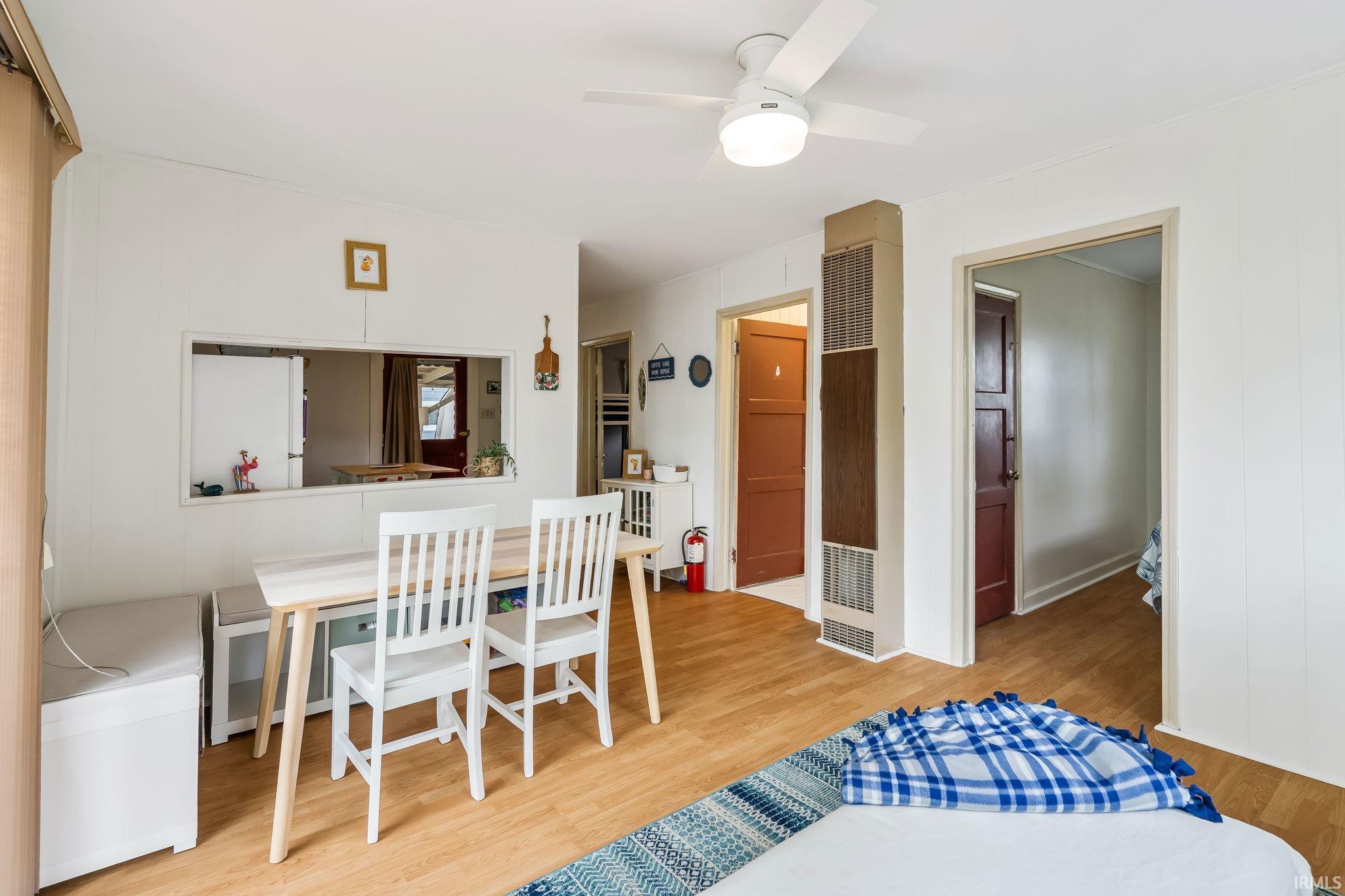 Dining area with wood-finish flooring, white paneled walls, and a ceiling fan with integrated lighting