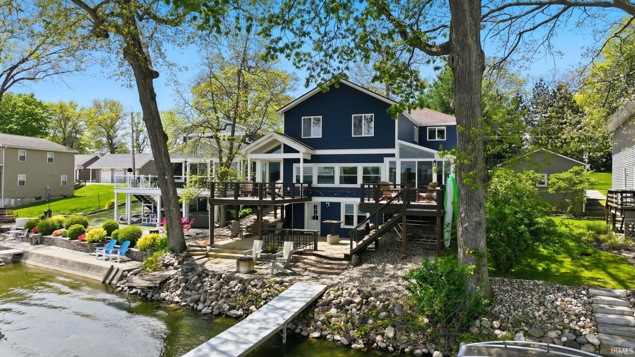 Waterfront residence featuring a spacious multi-level deck, direct water access with a private dock, and a concrete seawall