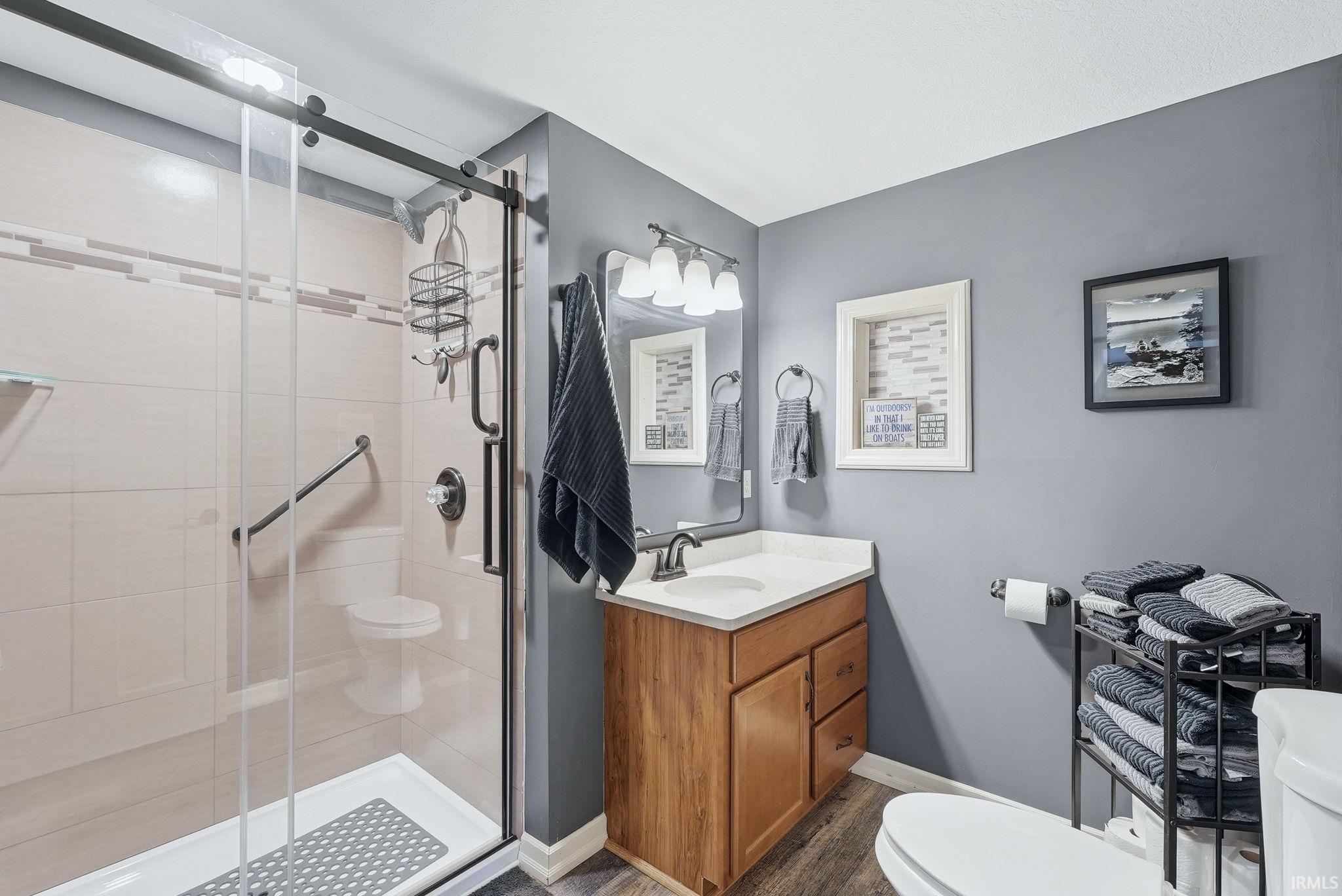 Full bathroom featuring a shower with a sliding glass door, a wood-finish vanity with a white countertop, and gray wall paint