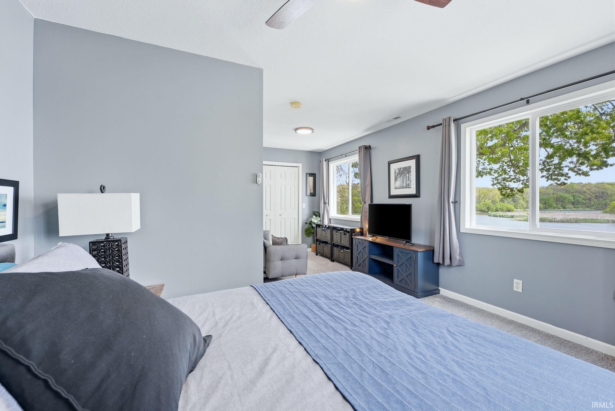 Spacious room featuring multiple windows, a ceiling fan, and light gray wall finishes