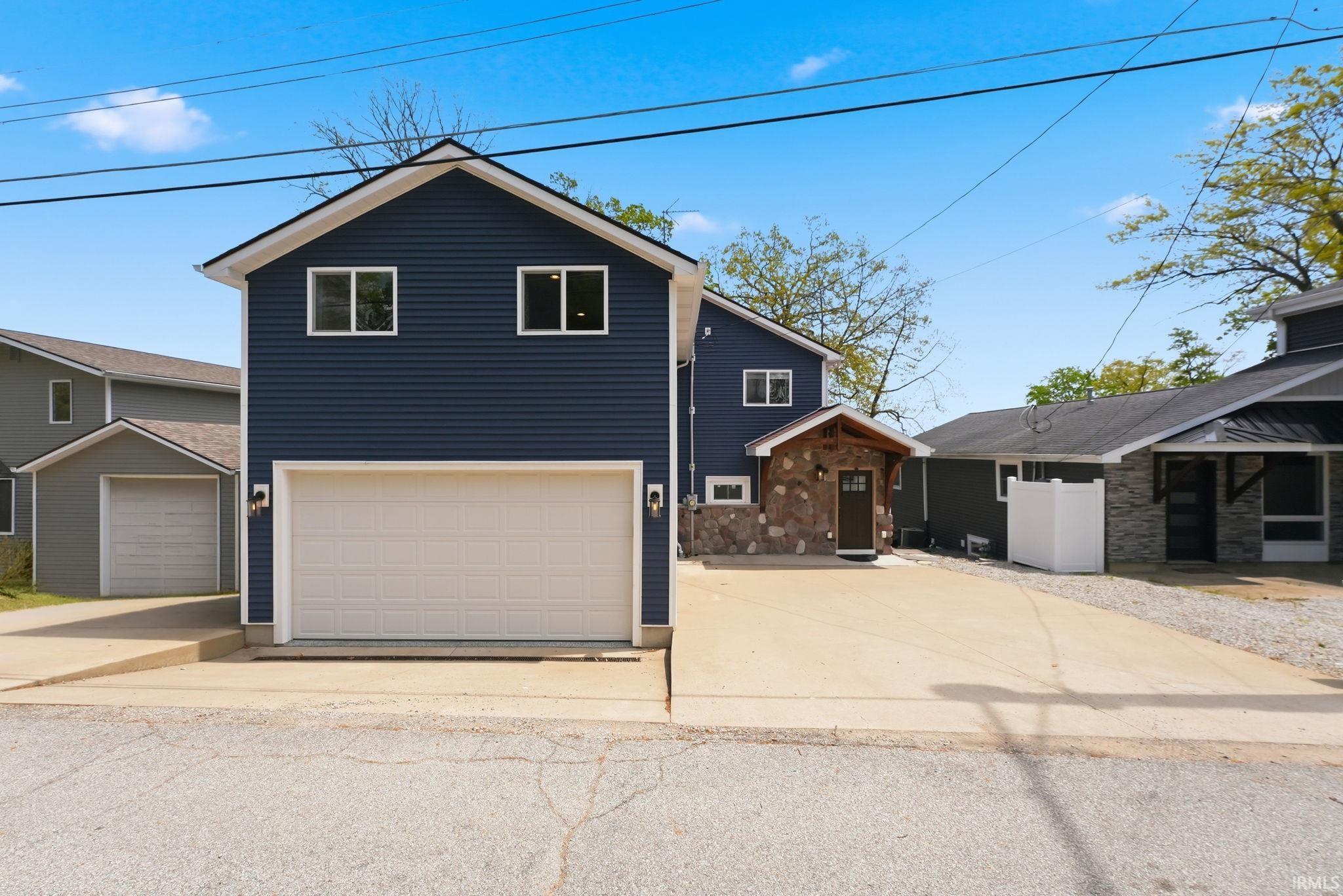 Contemporary two-story home featuring dark blue horizontal siding and a two-car garage