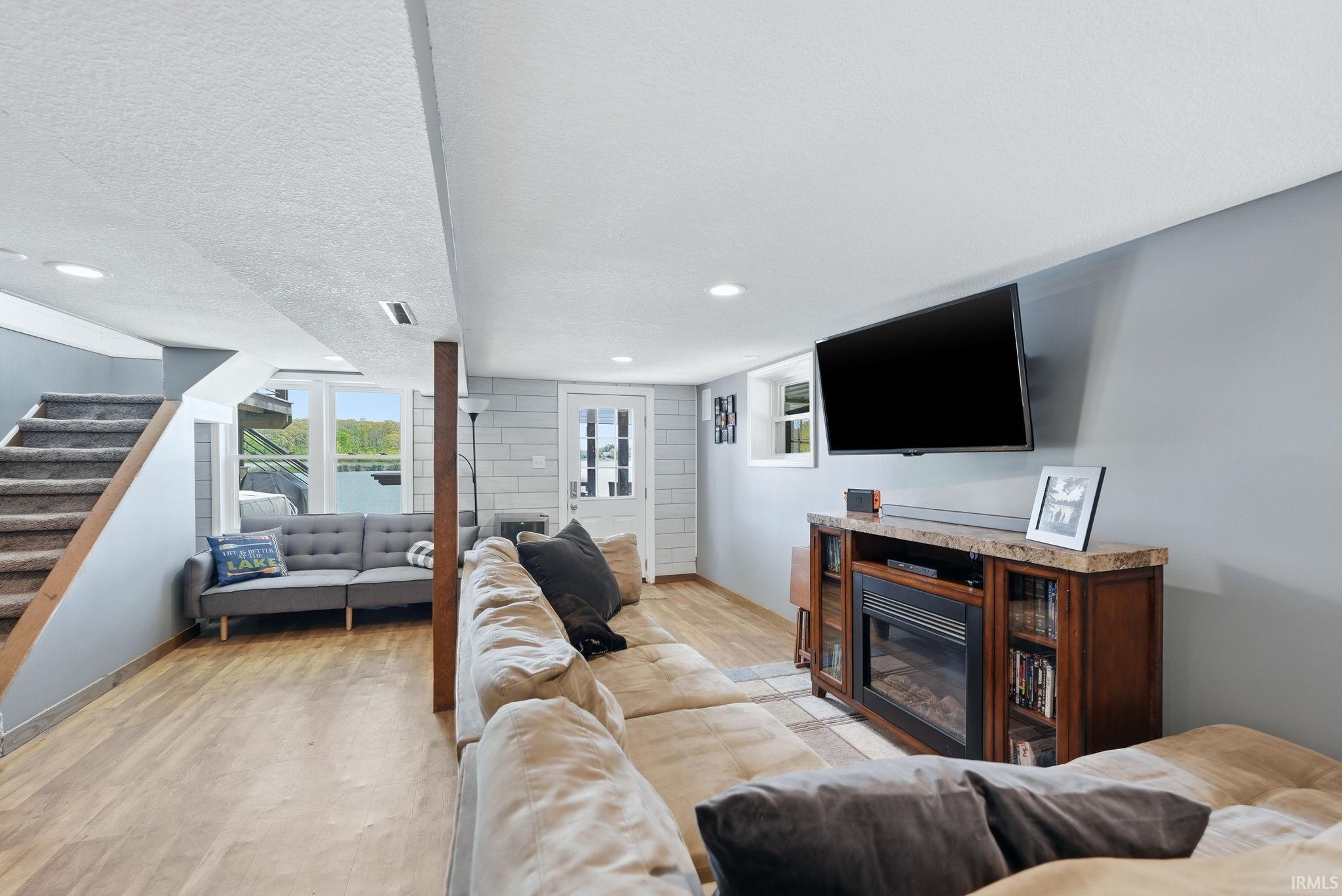 Finished living space featuring wood-finish flooring, a built-in fireplace media console, and recessed lighting