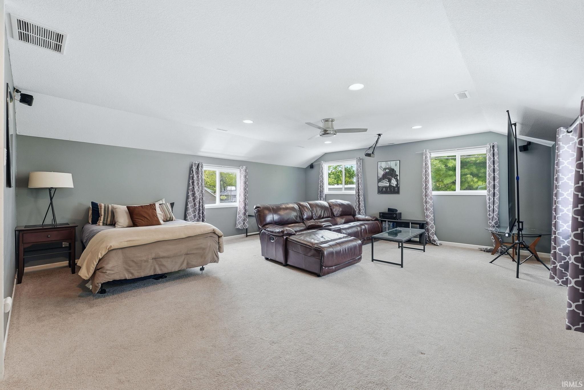 Spacious room featuring light-colored carpeting, multiple windows providing natural light, and recessed lighting