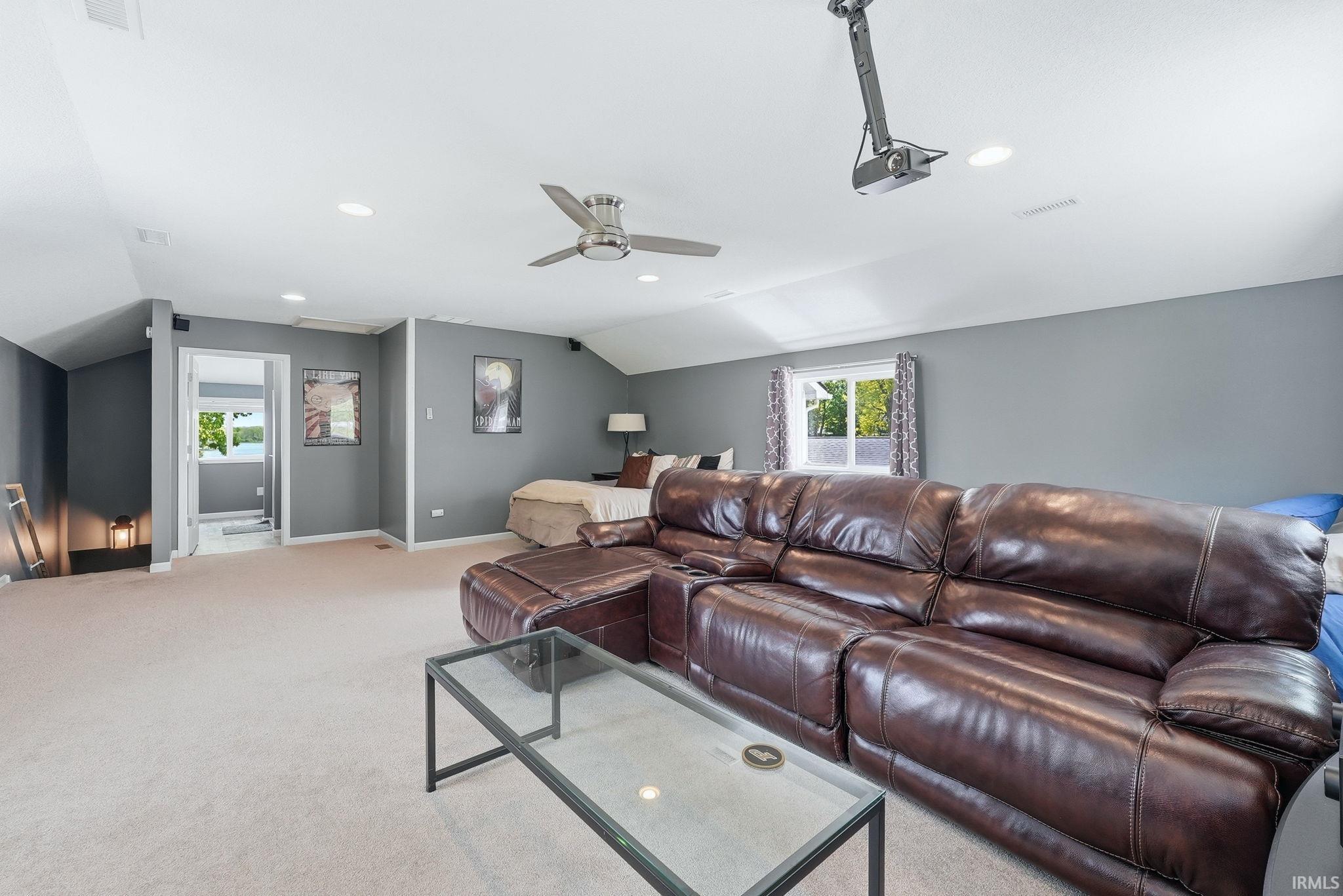 Carpeted room with sloped ceilings, recessed lighting, ceiling fan, and window with exterior view