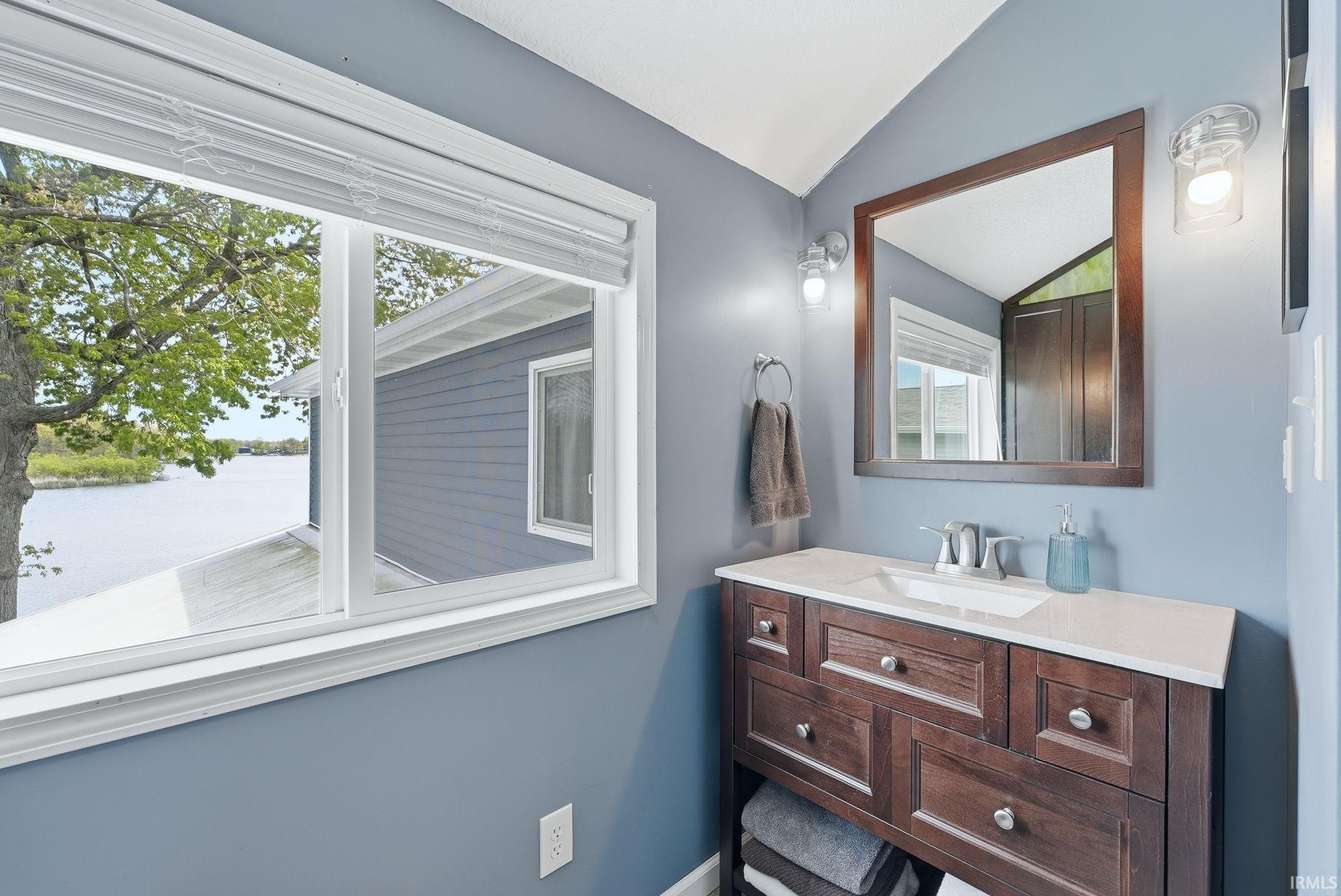 Bathroom featuring a window with water, tree, and exterior siding visible