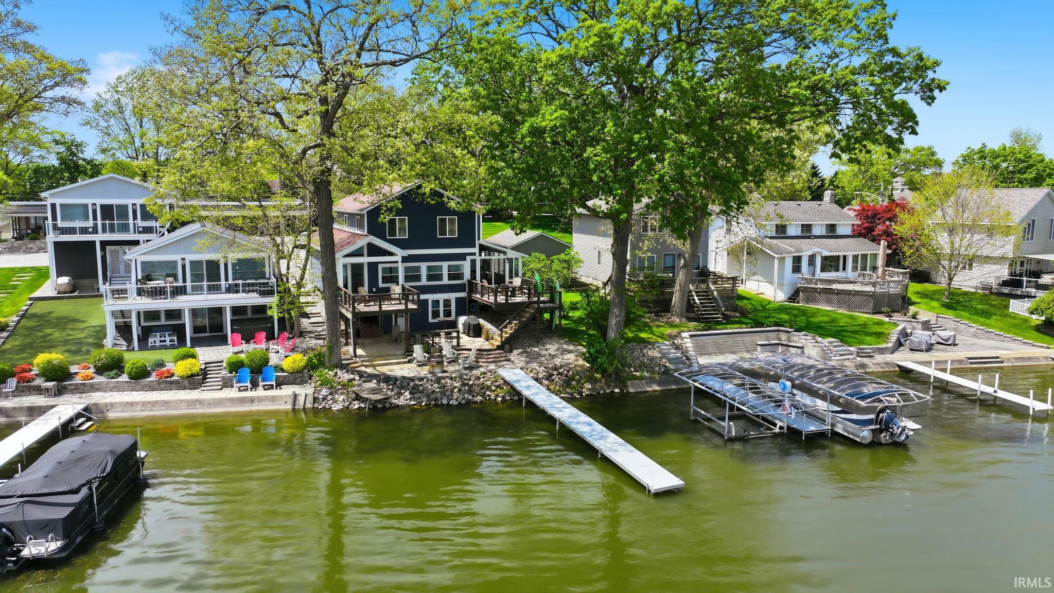 Waterfront residence featuring multiple decks, established landscaping, private dock, and an integrated boat lift system