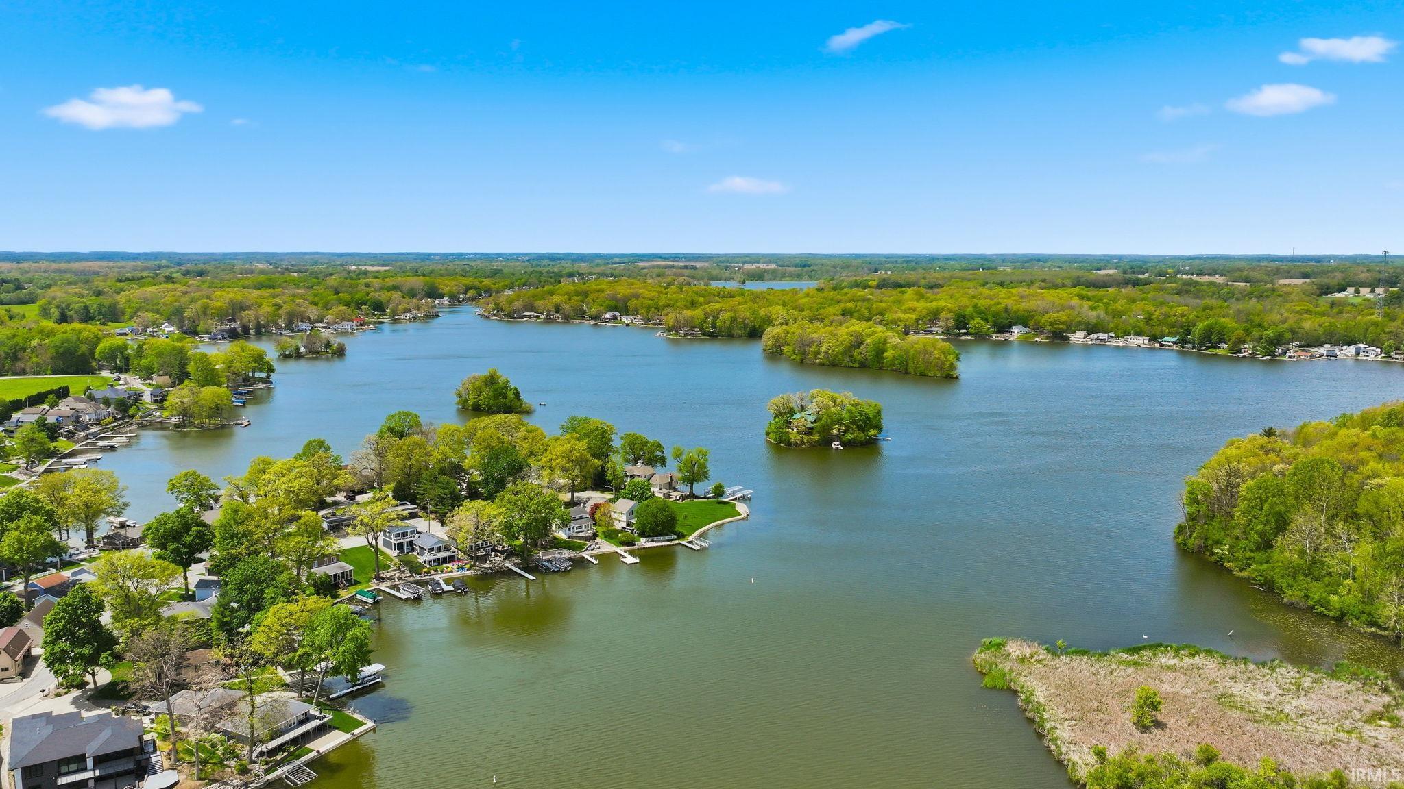 Expansive lake featuring numerous waterfront properties, lush green trees, and multiple islands