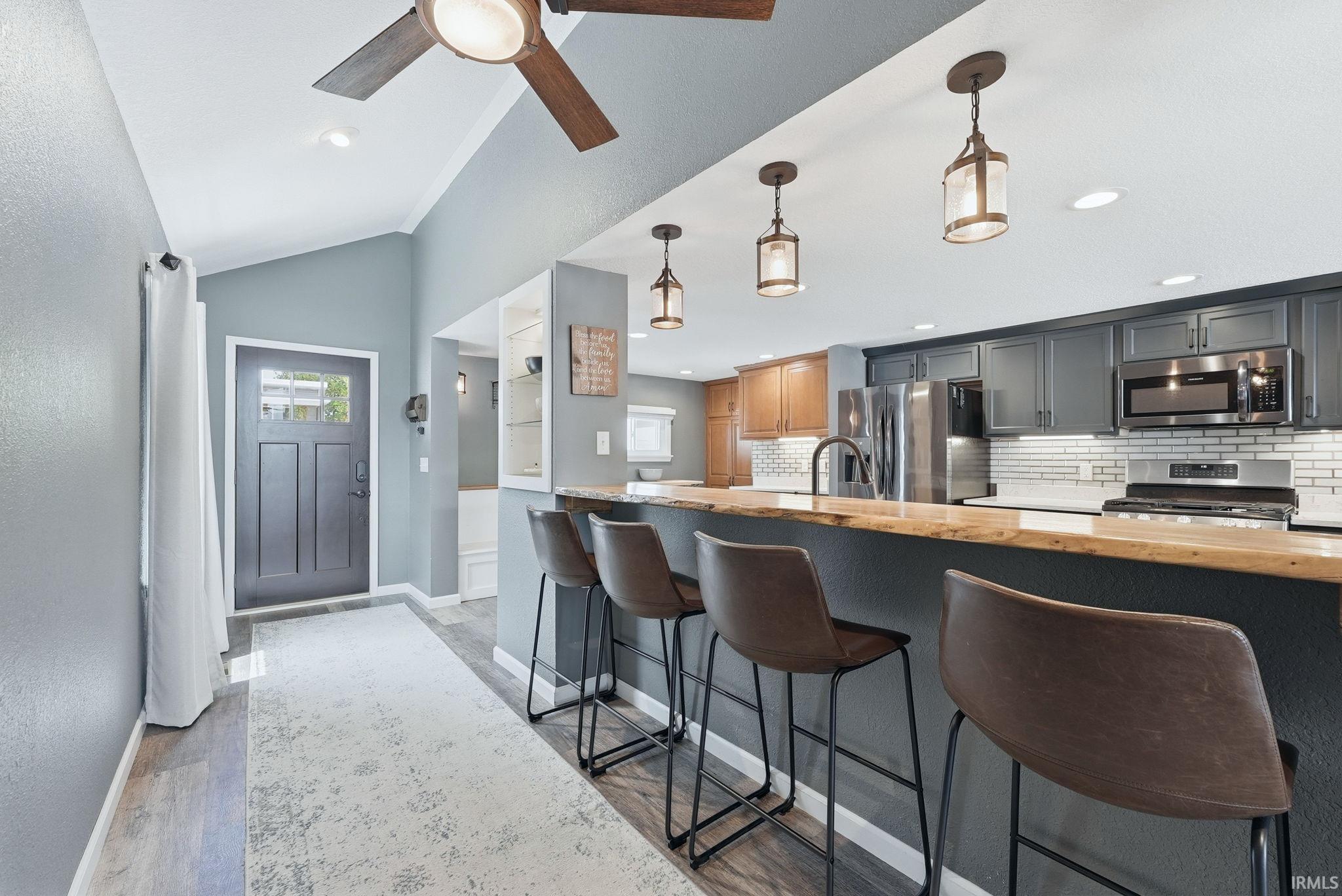 Open-concept kitchen with a live-edge wood breakfast bar, stainless steel appliances, and white subway tile backsplash
