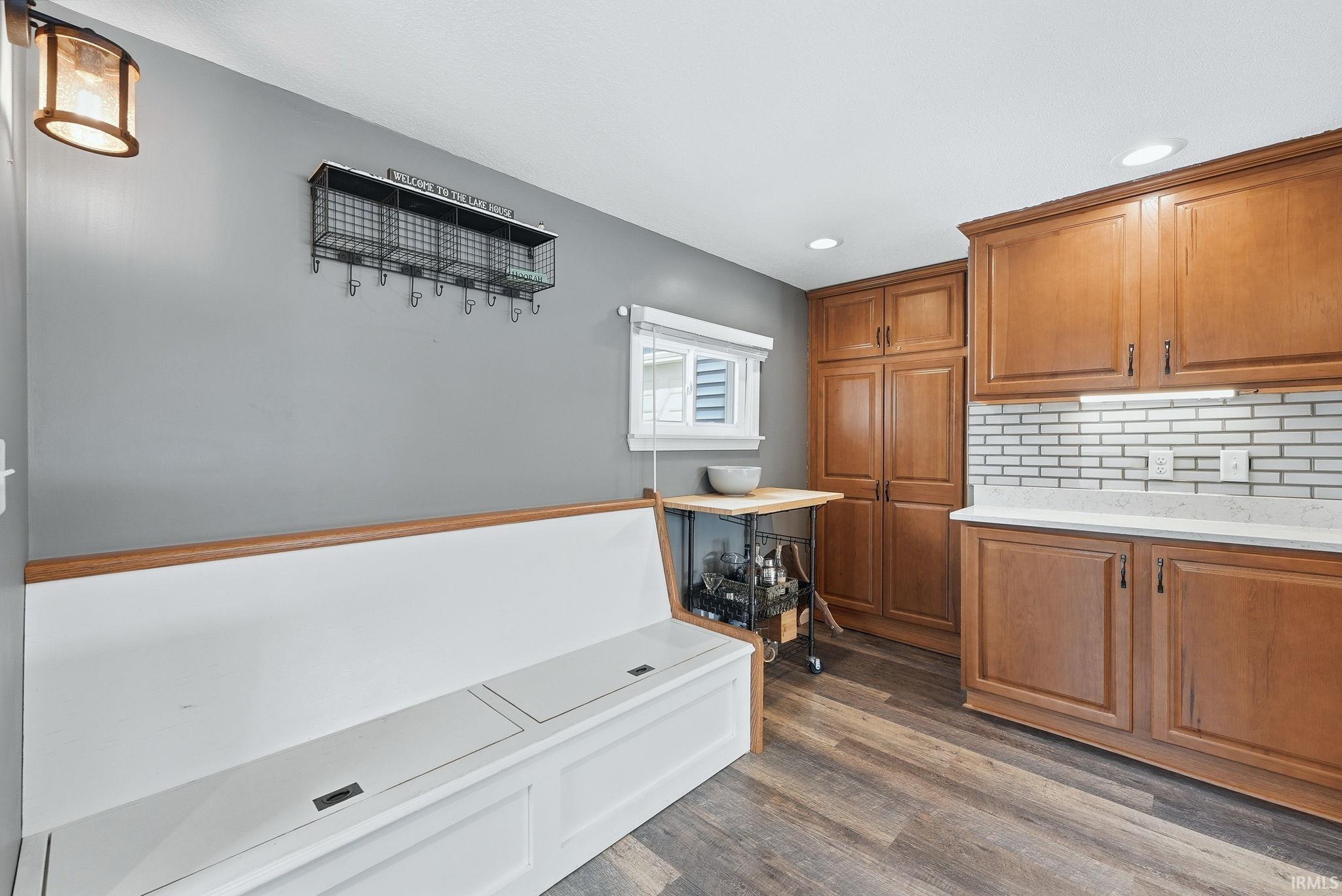 Kitchen area featuring wood-finish flooring, a built-in white bench with storage, and recessed lighting