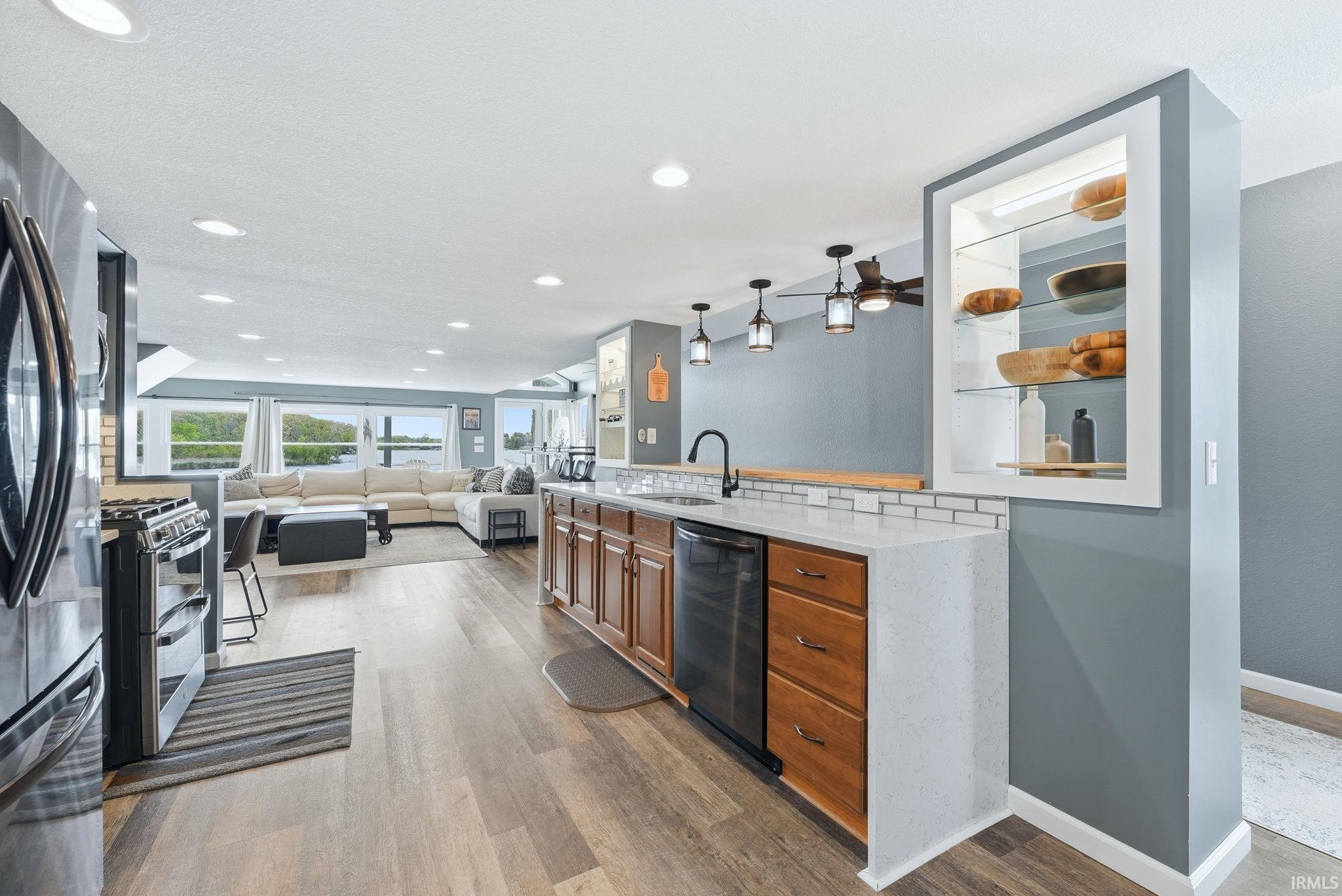 Open-concept kitchen featuring wood-finish flooring, recessed lighting, and a peninsula with a light-colored countertop and subway tile backsplash