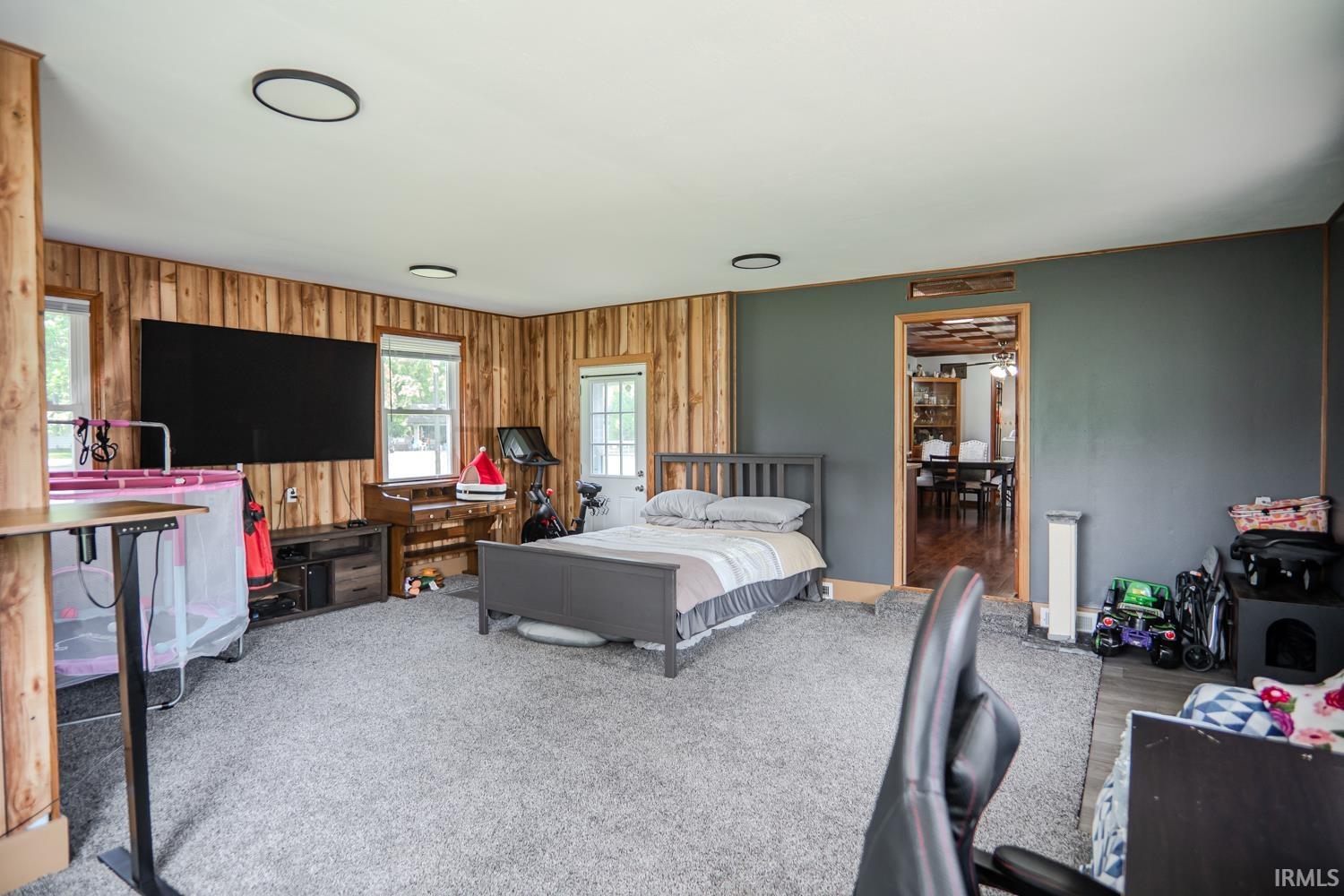 Spacious room featuring wood paneling on two walls and a neutral-toned accent wall