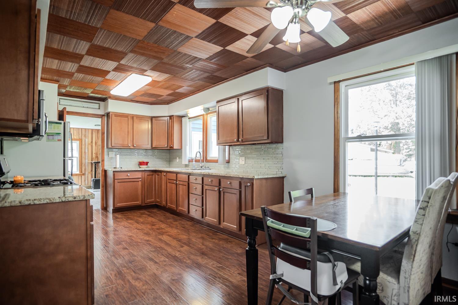 Kitchen featuring rich wood-finish flooring and cabinetry, granite-style countertops, and a subway tile backsplash