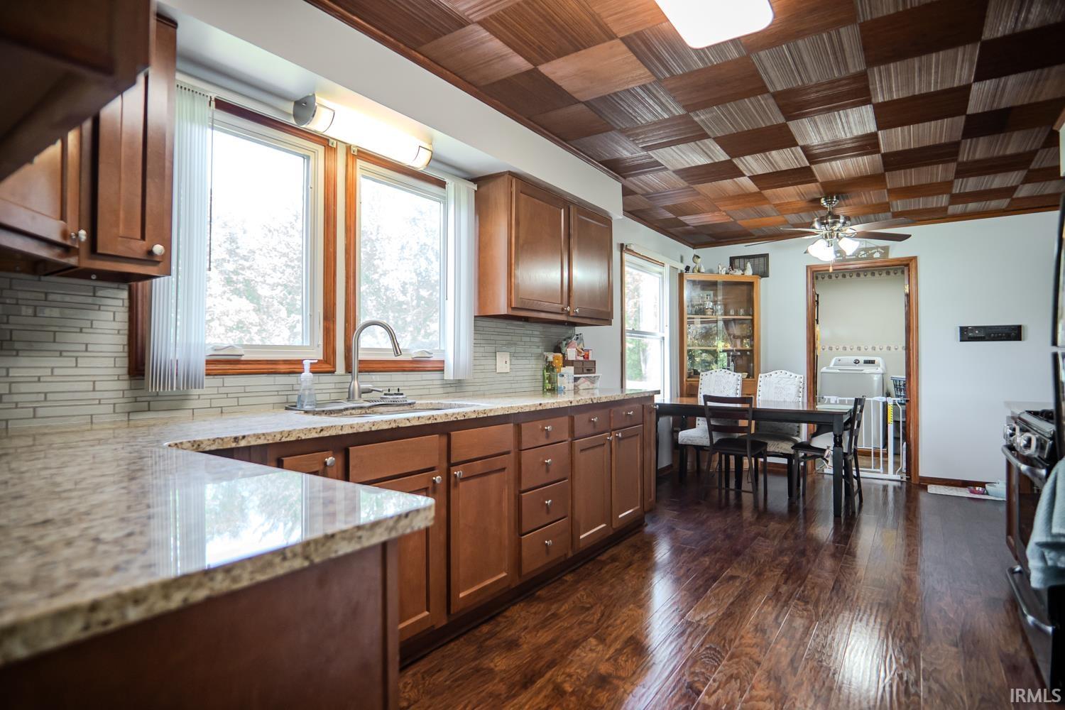Kitchen featuring warm-toned cabinetry, light-toned granite countertops, and a subway tile backsplash