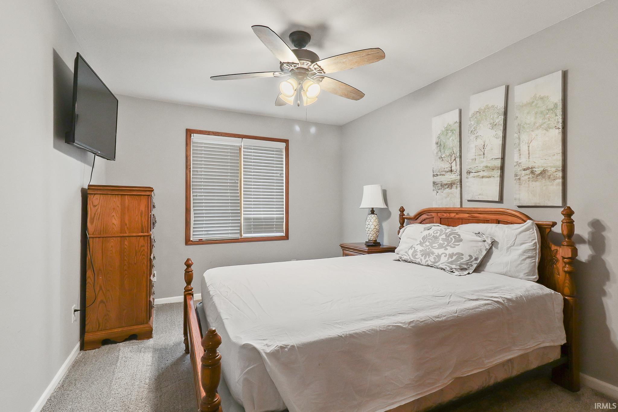 Carpeted room with a ceiling fan light fixture, a window with horizontal blinds, and neutral grey wall paint