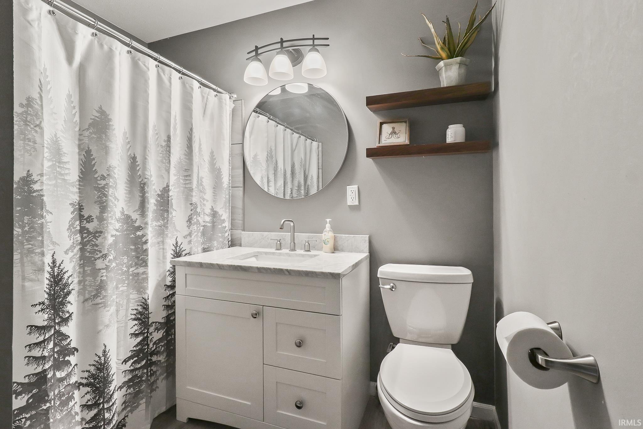Bathroom featuring a white vanity with a light-colored countertop and a round mirror