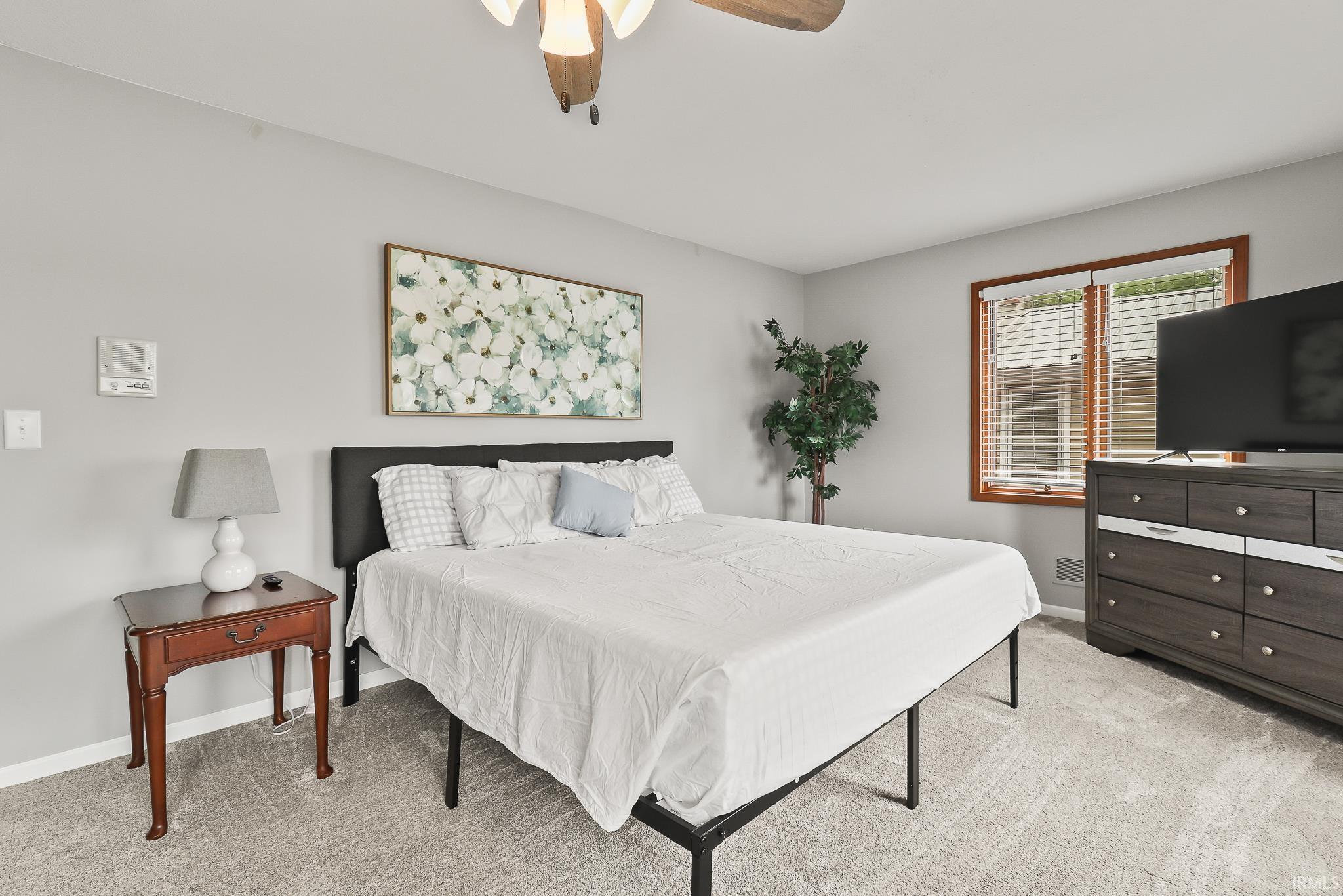 Carpeted room with light gray walls, a window with wood trim and blinds, and a ceiling fan with integrated lighting