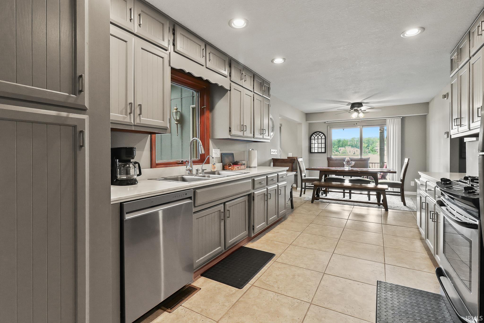 Kitchen featuring contemporary gray cabinetry, stainless steel appliances, and light-toned tile flooring