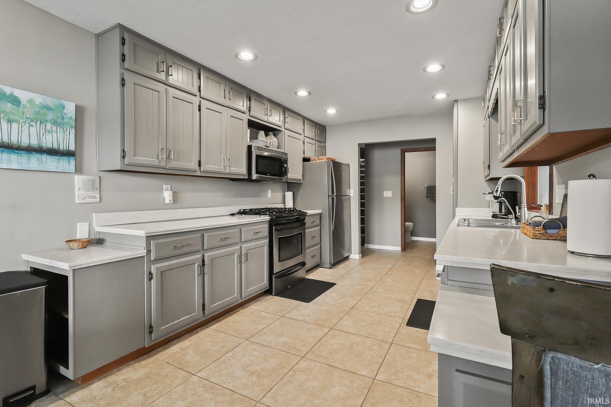 Kitchen featuring extensive gray cabinetry, light-toned countertops, stainless steel appliances, recessed lighting, and tile flooring