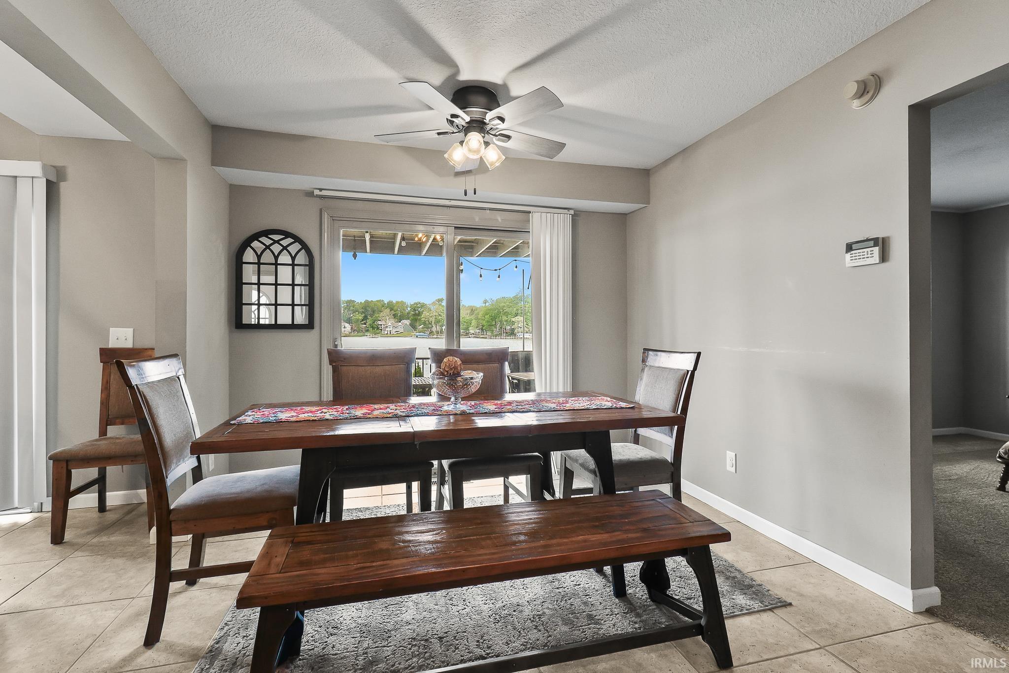 Dining area featuring tile flooring, neutral wall tones, a ceiling fan with integrated lighting, and a sliding glass door opening to an outdoor space