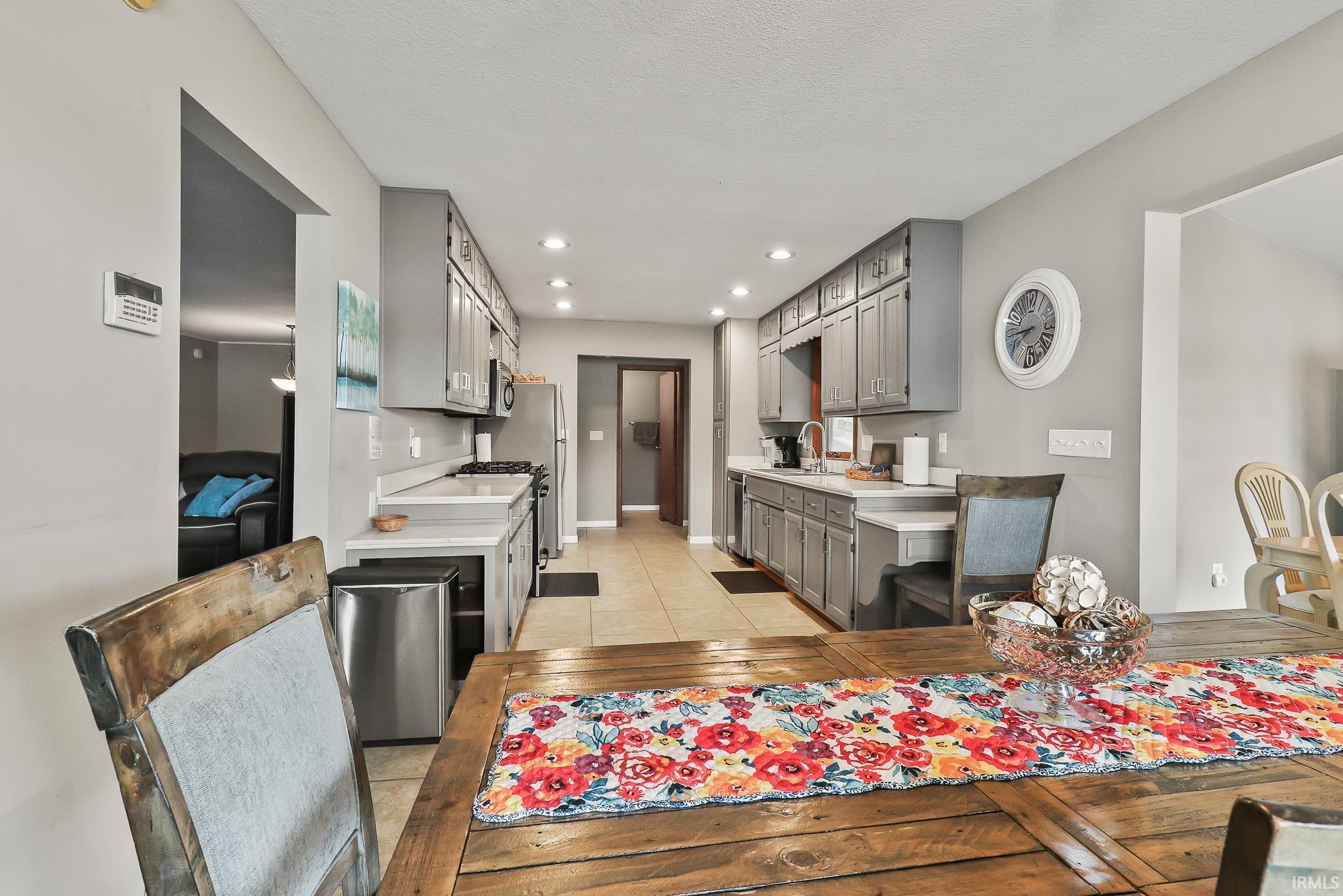 Galley-style kitchen featuring grey cabinetry, white countertops, tile flooring, and recessed lighting