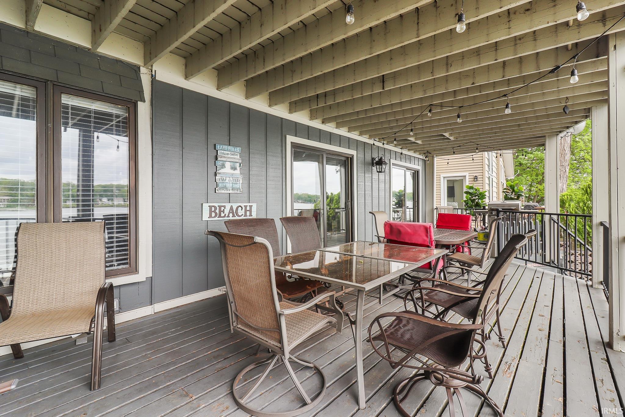 Covered deck featuring a wood floor, gray siding, and exposed ceiling joists
