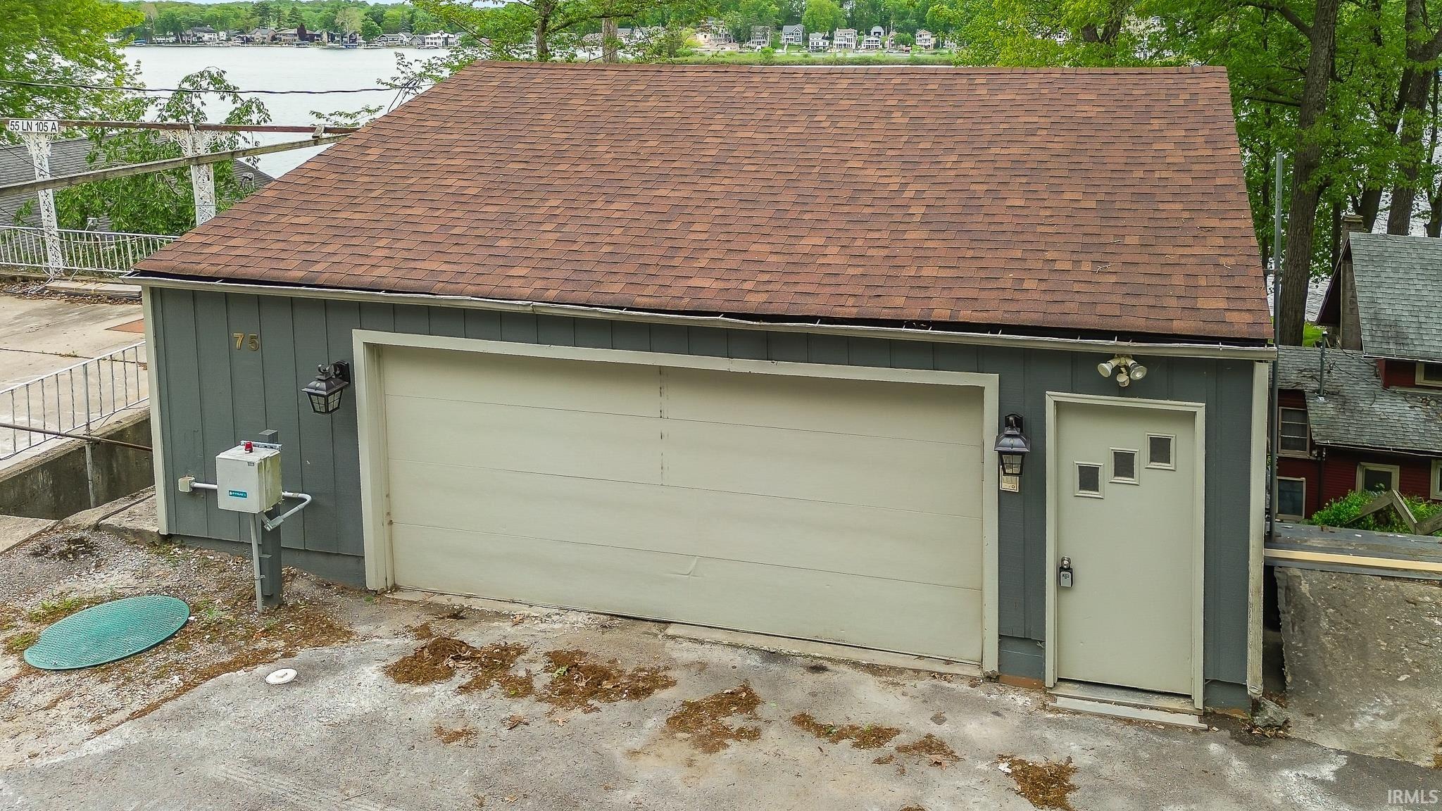 Detached garage structure featuring a brown shingle roof and grey siding