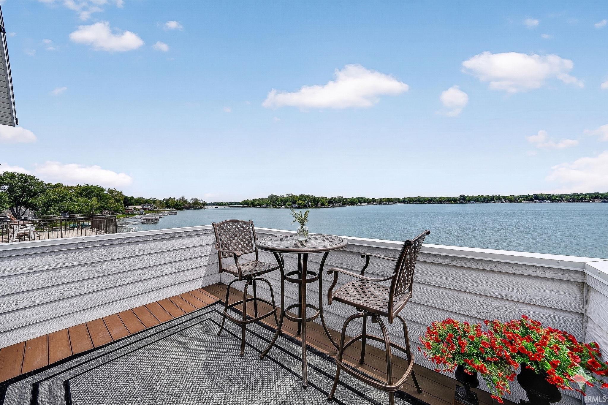 Outdoor balcony featuring composite decking, gray horizontal siding, and metal railings overlooking a body of water