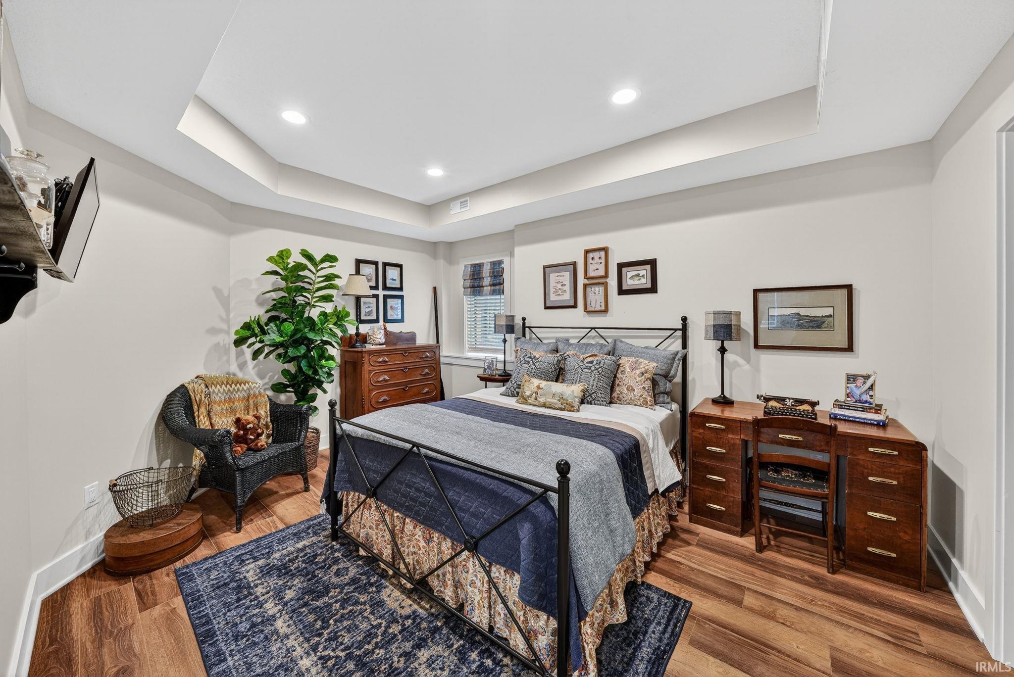 Tray ceiling with recessed lighting above wood-finish flooring
