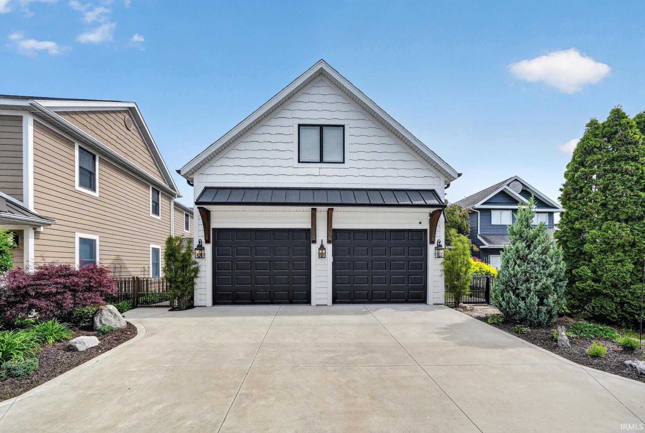 Two-car garage with black panel doors and exterior lighting fixtures