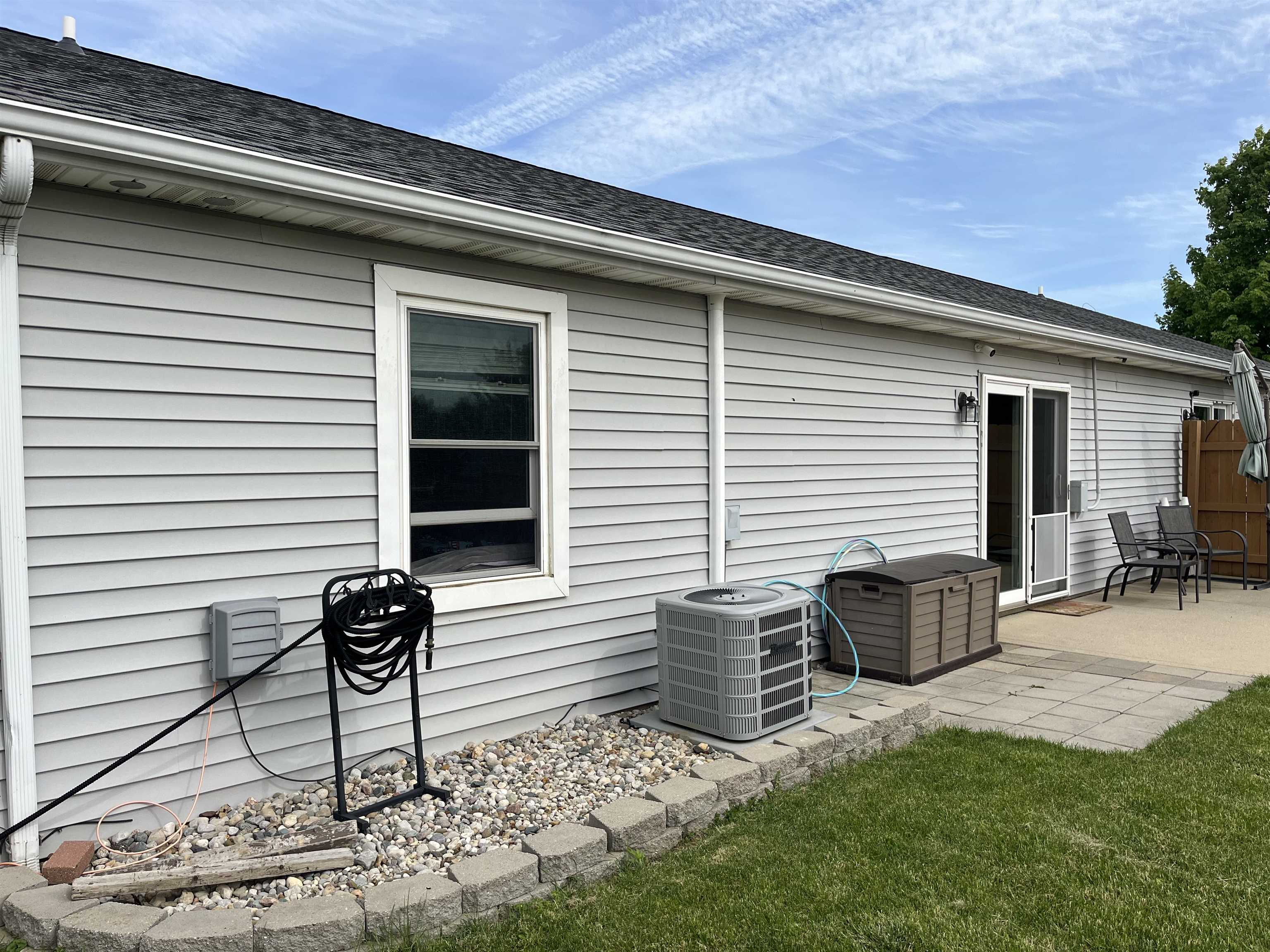 Exterior featuring light gray horizontal siding, a dark shingle roof, and white gutters