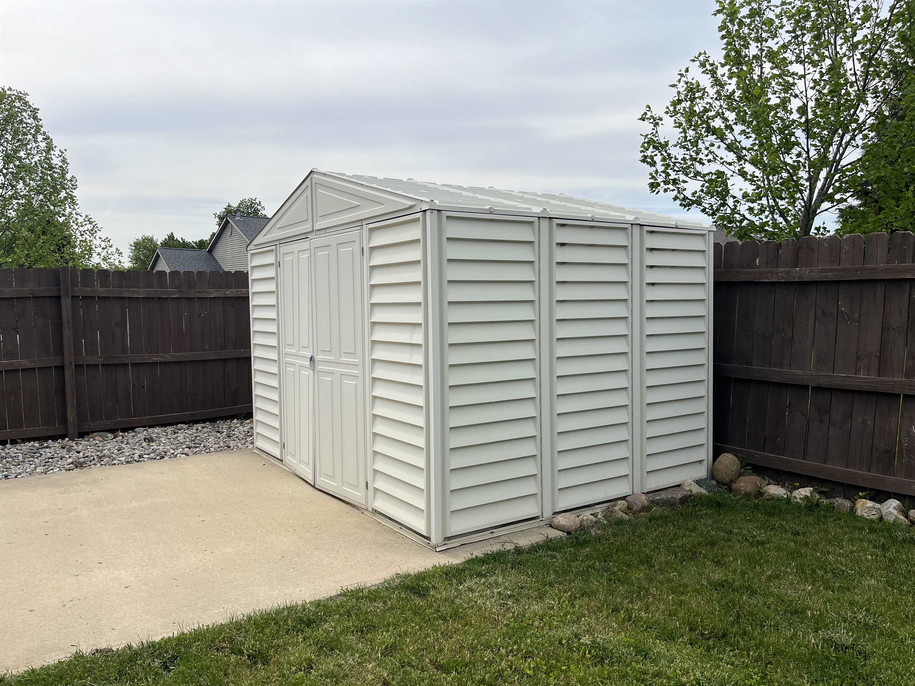 White utility shed with a gable roof, double doors, and horizontal siding