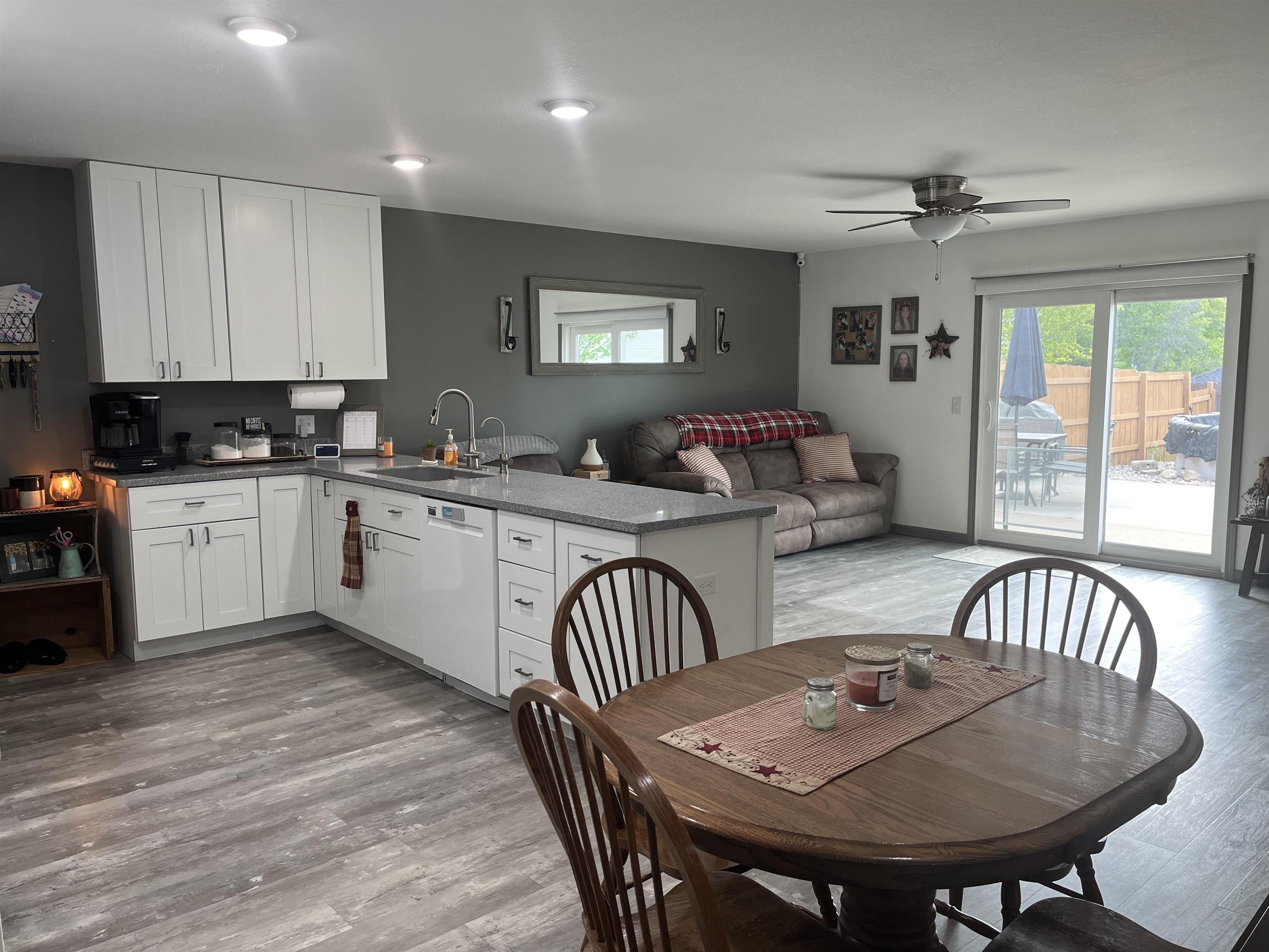 Open-concept living area featuring an eat-in kitchen with white cabinetry and a light-toned countertop