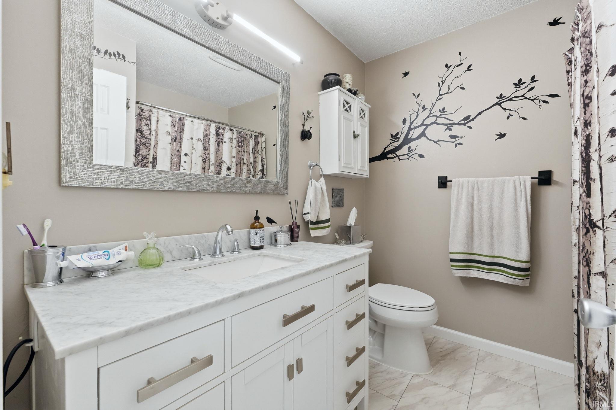 White vanity with brushed nickel hardware, a rectangular undermount sink, stone countertop and large linen closet