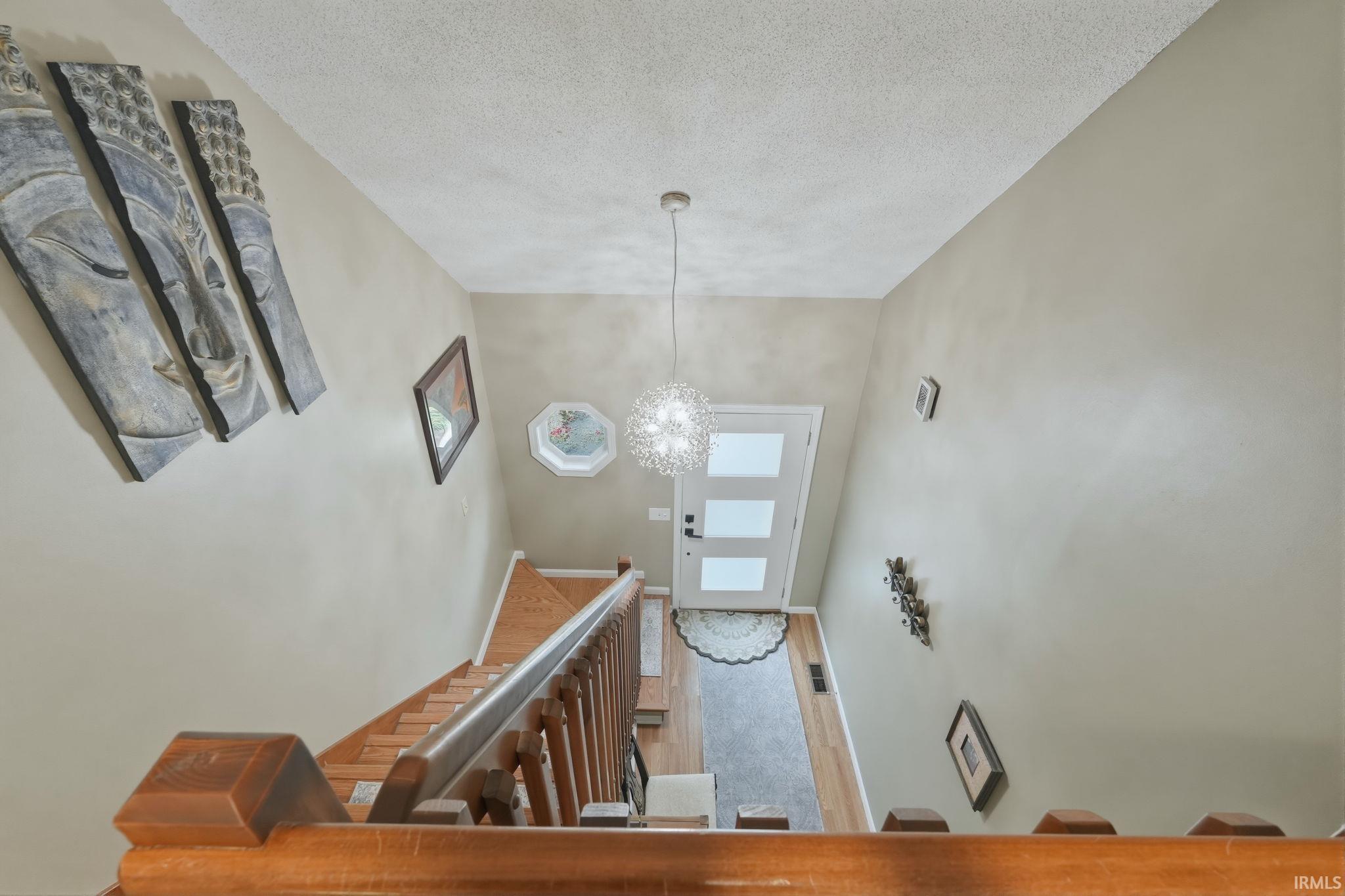 Foyer featuring a modern white entry door with three rectangular lites, a contemporary pendant light fixture, and light wood-finish flooring