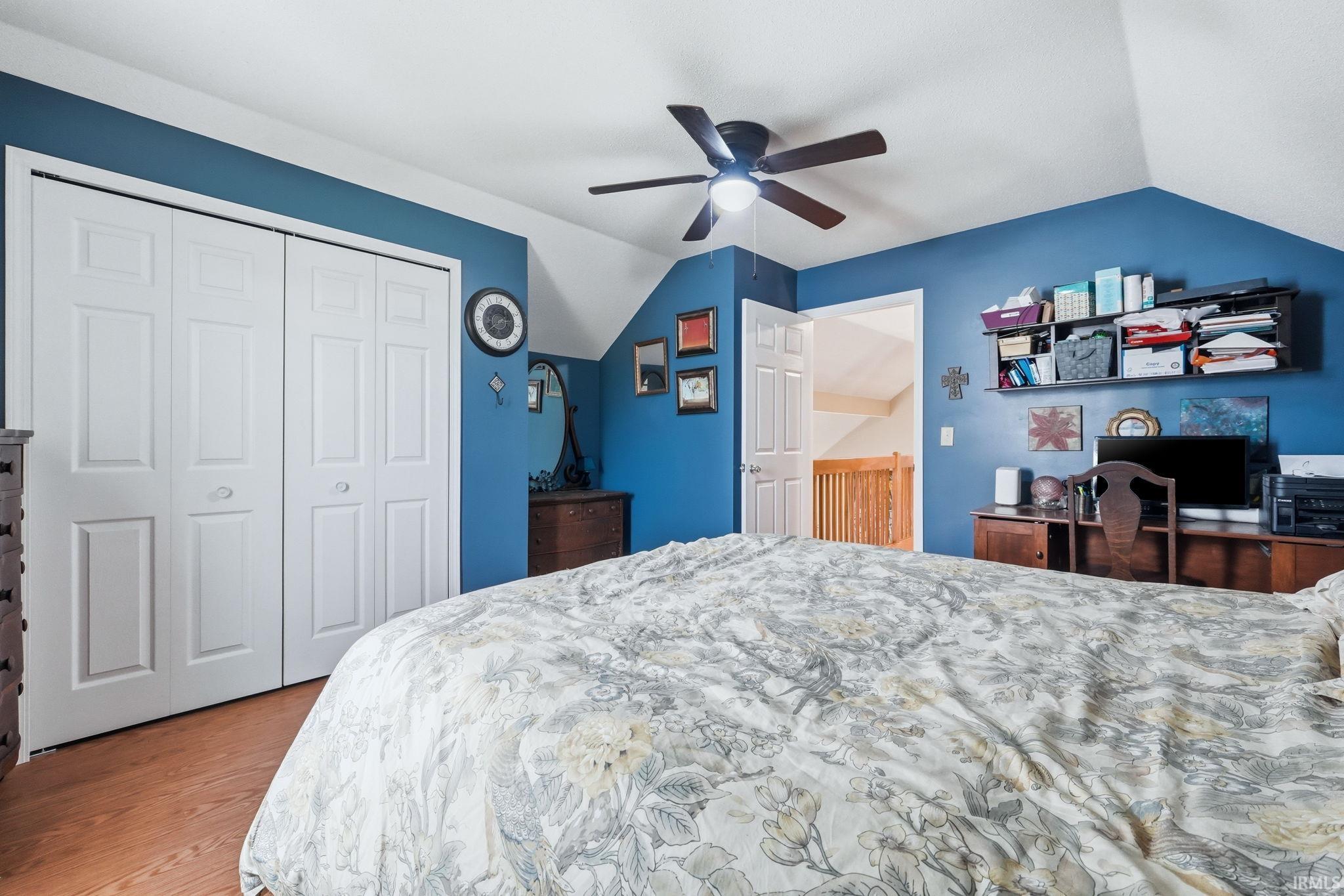Bedroom featuring wood-finish flooring, a ceiling fan with integrated lighting, and white bi-fold closet doors