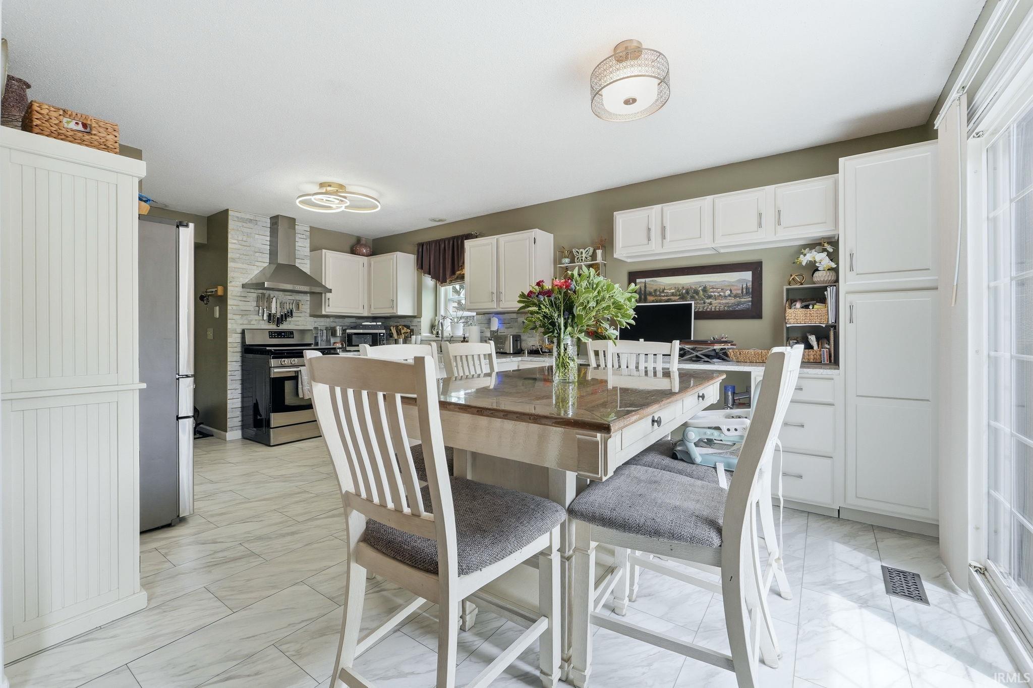 Kitchen featuring a penninsula with quartz countertops, white cabinetry, stainless steel appliances, and light-toned plank flooring
