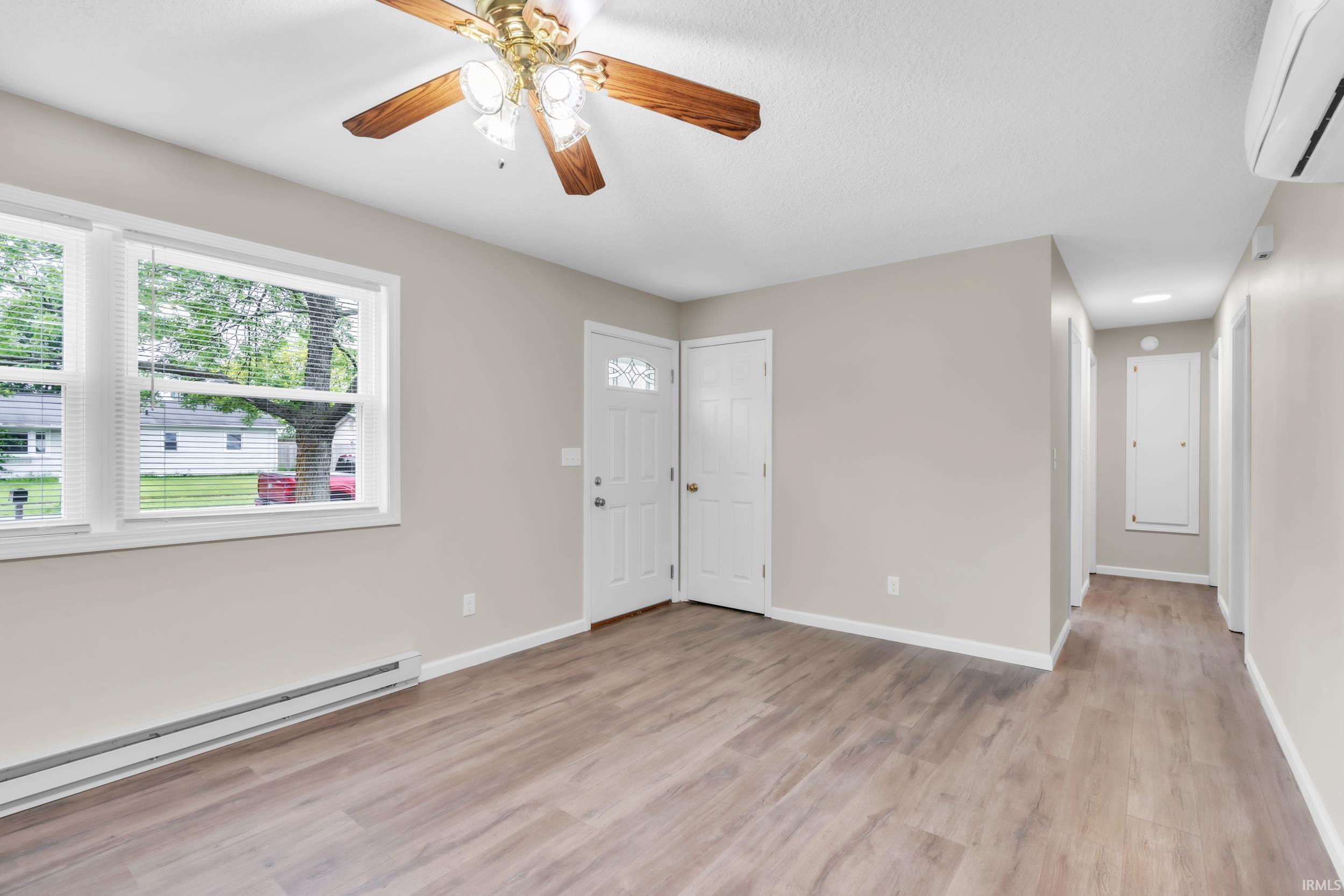 Spacious room featuring wood-finish flooring, light neutral wall tones, and white trim