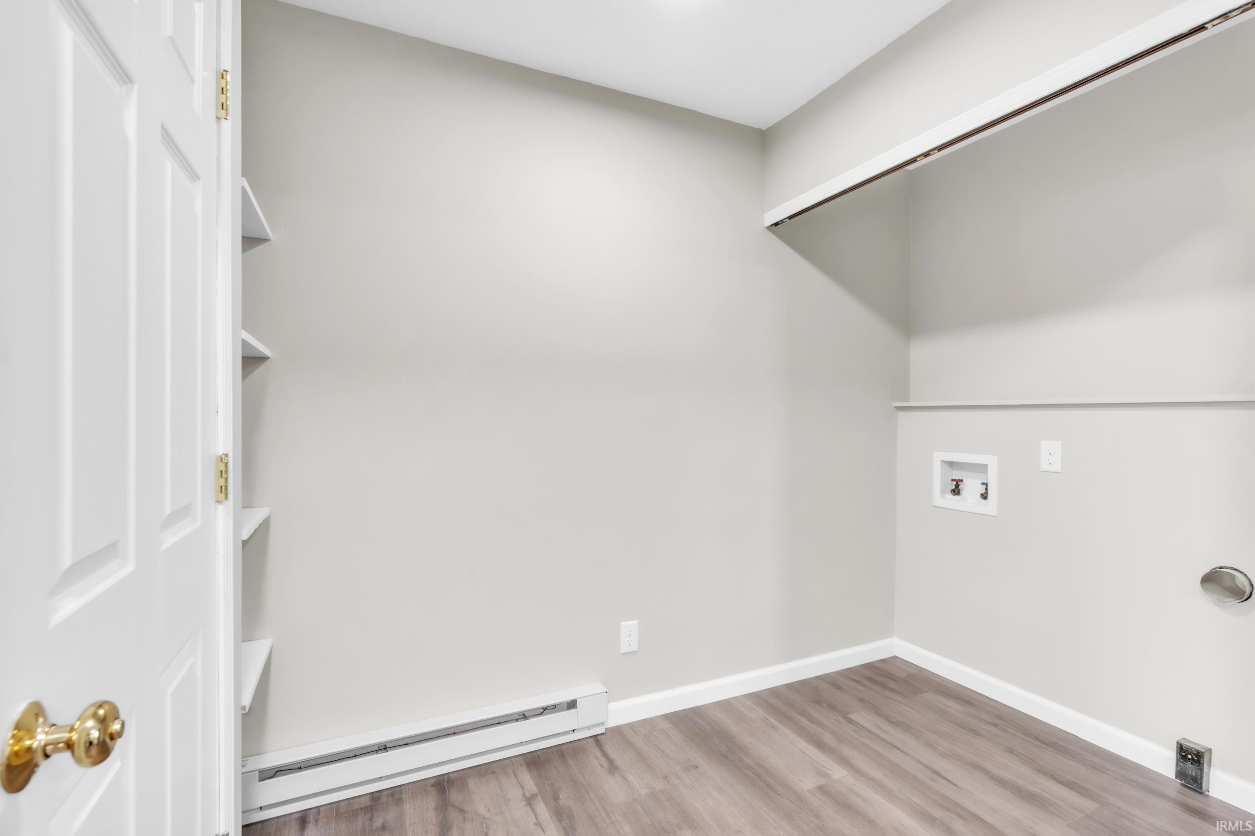 Dedicated laundry area featuring modern wood-finish flooring, light gray wall paint, and built-in shelving