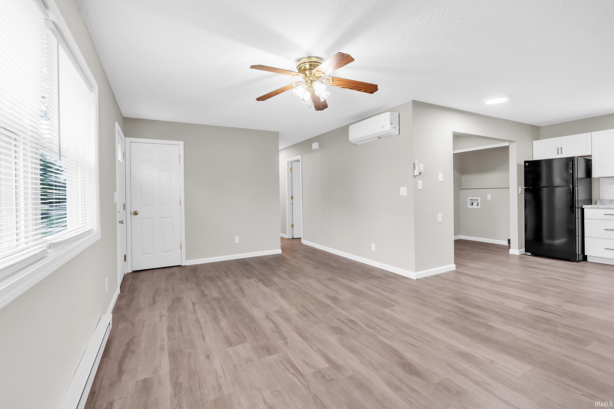 Open-concept living space featuring wood-finish flooring, a ceiling fan, and light gray walls